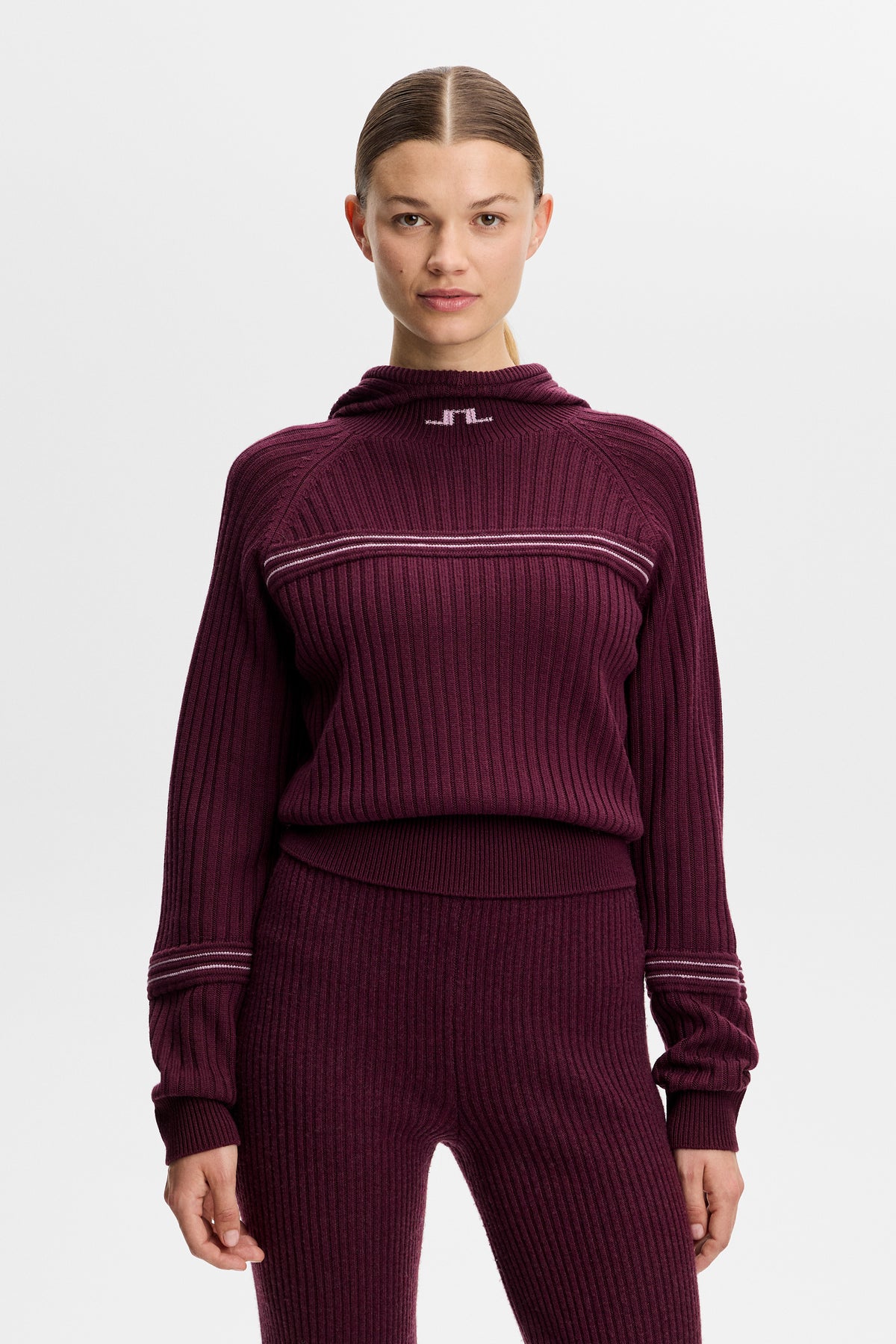 Framifrån: Hilda Knitted Rib Hoodie i Winetasting med ribbad struktur, huva och stickad Bridge-logotyp vid halsen.