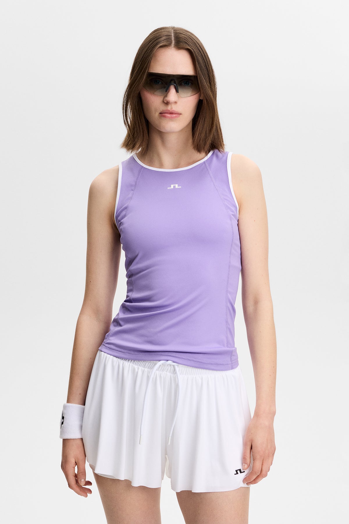 Vorderansicht: Danaya Top in Paisley Purple mit weißer Einfassung und Bridge-Logo an einem Model mit weißen Shorts.