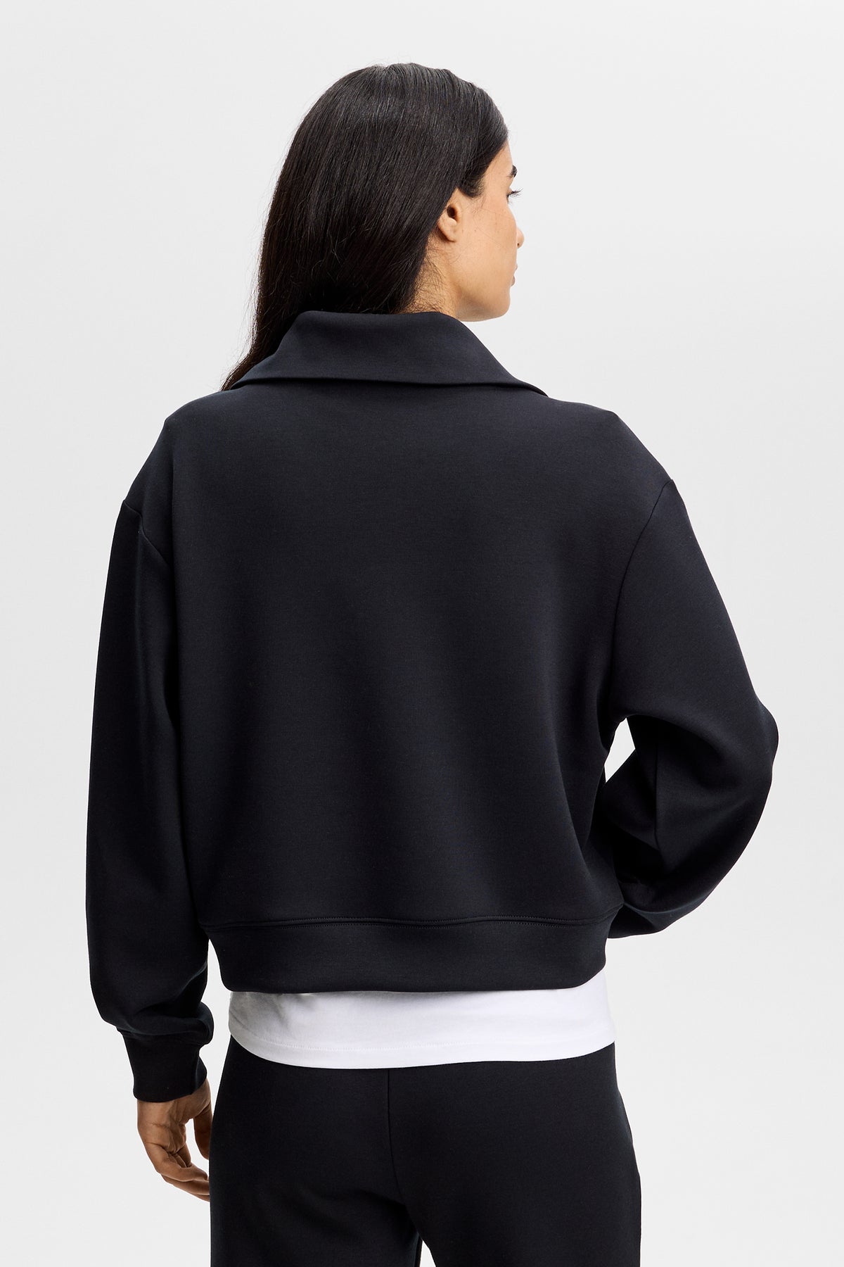 Set bagfra: Sort Funnel Zip Sweatshirt med høj krave og lange ærmer, båret over en hvid top.