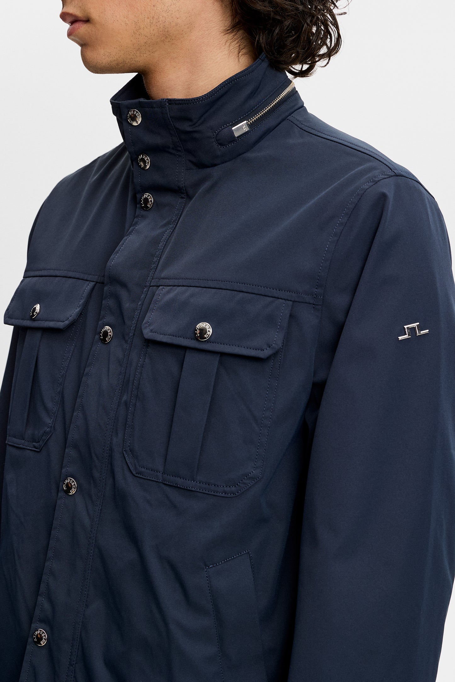 Close-up of Bailey Recy Poly Jacket in JL Navy with flap chest pockets, zip collar, and sleeve Bridge logo.