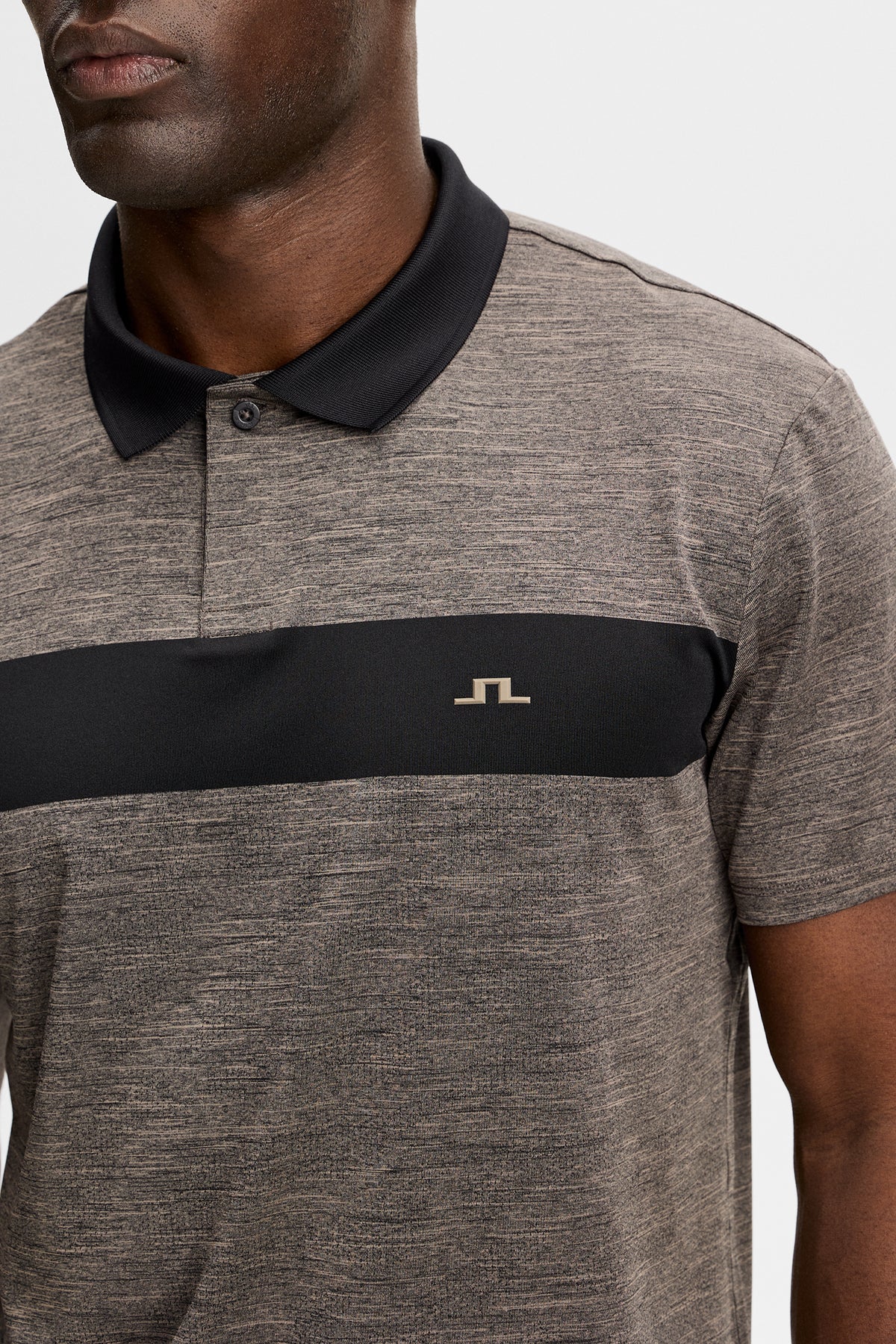 Nahaufnahme: Rocky Polo in Brindle Melange mit kontrastierendem Bruststreifen, schwarzem Kragen und Bridge-Logo.