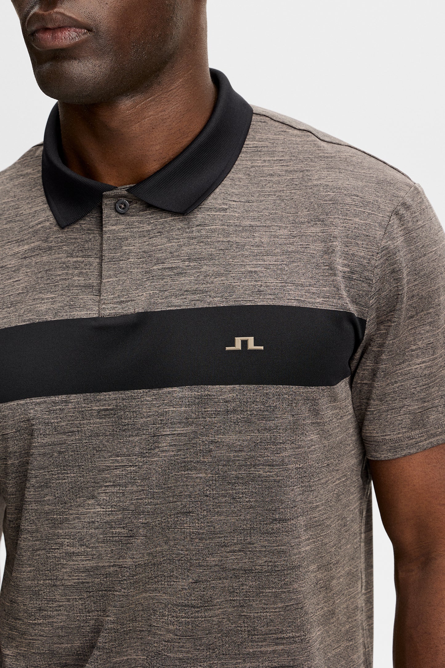 Nahaufnahme: Rocky Polo in Brindle Melange mit kontrastierendem Bruststreifen, schwarzem Kragen und Bridge-Logo.