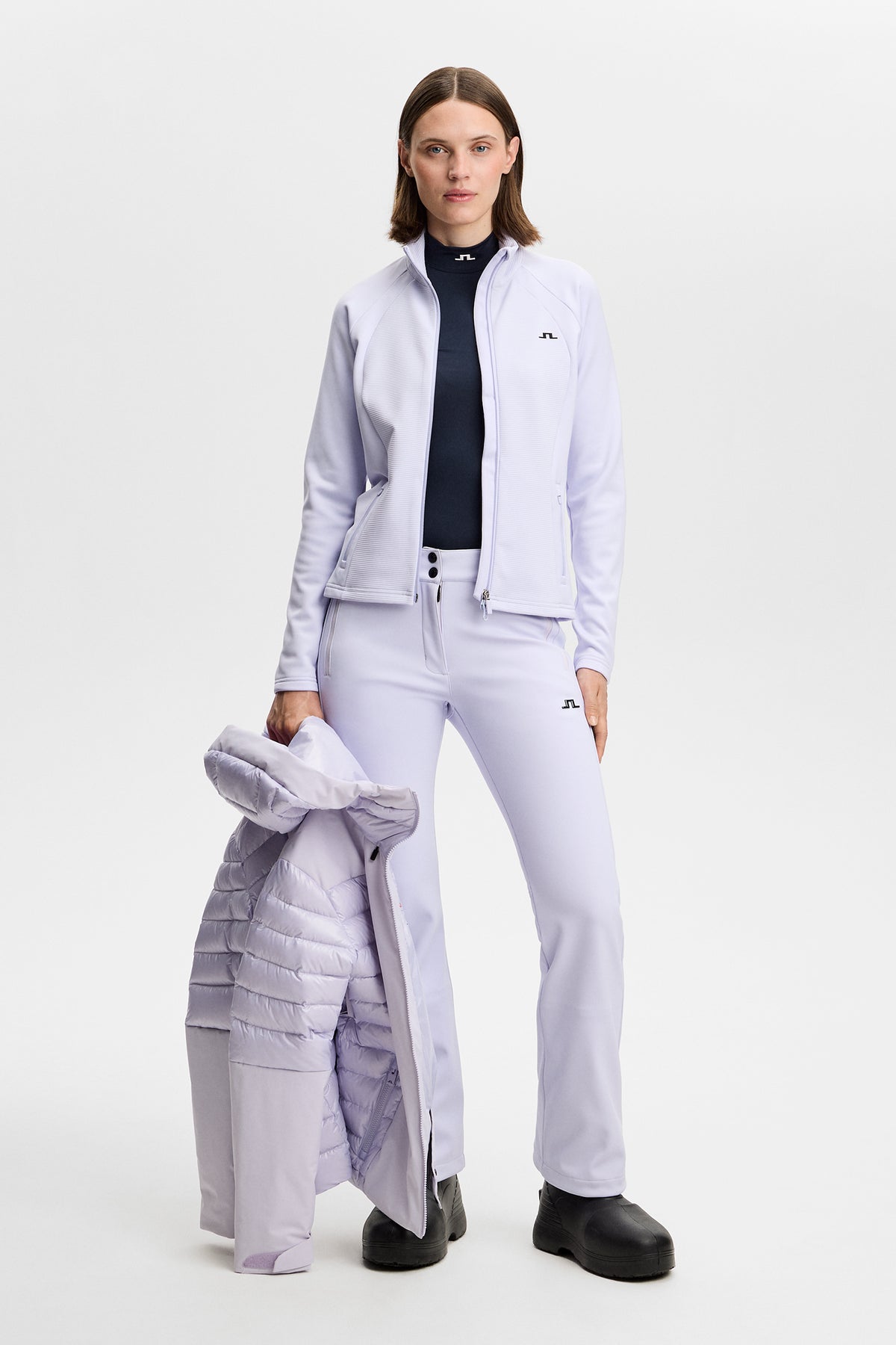 Vooraanzicht: Model draagt de Mireya Full Zip Mid Layer in Purple Heather met bijpassende skibroek en jas.