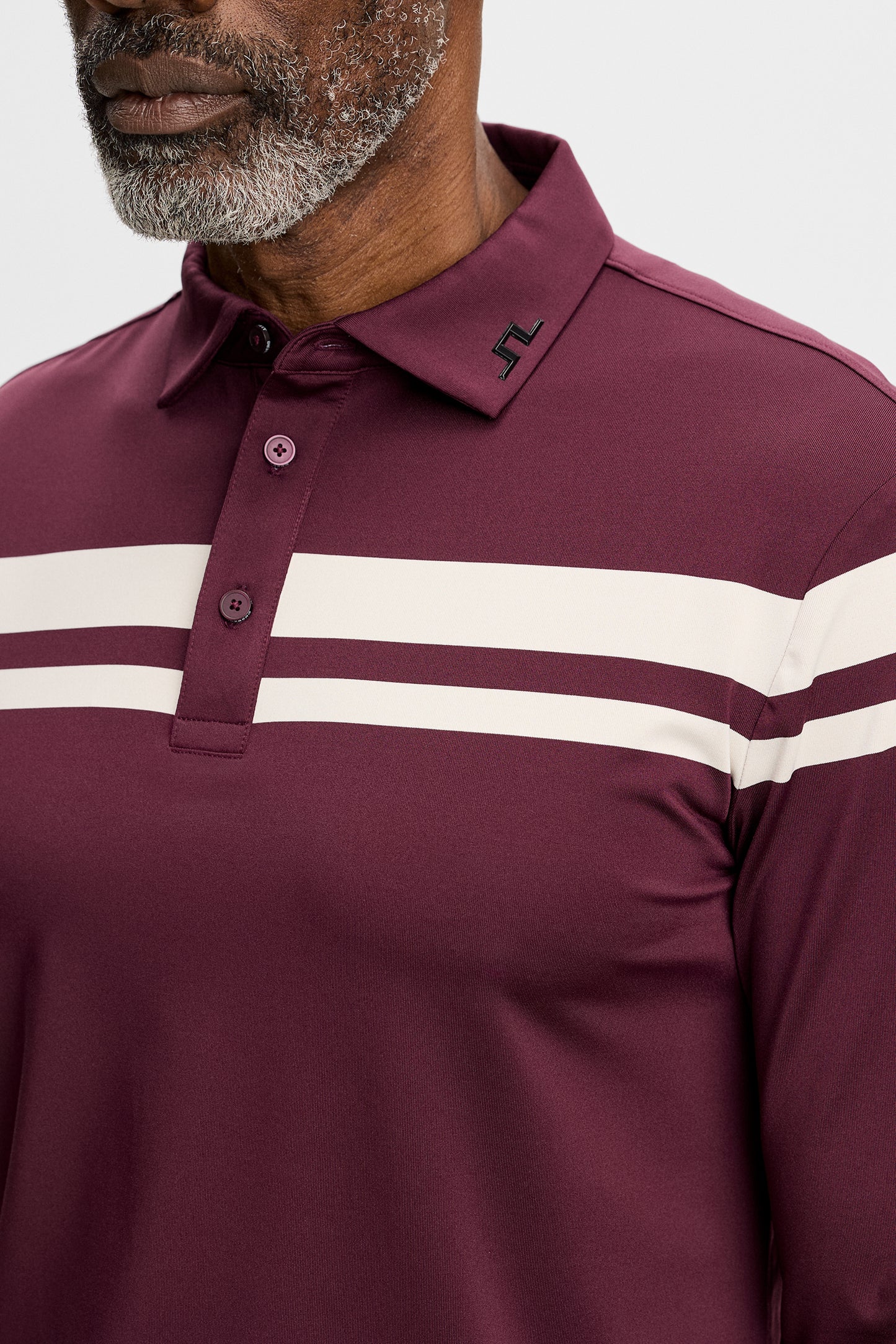 Nærbillede: Kenny LS Stripe Polo i vinrød med striber over brystet, knapstolpe og Bridge-logo på kraven.