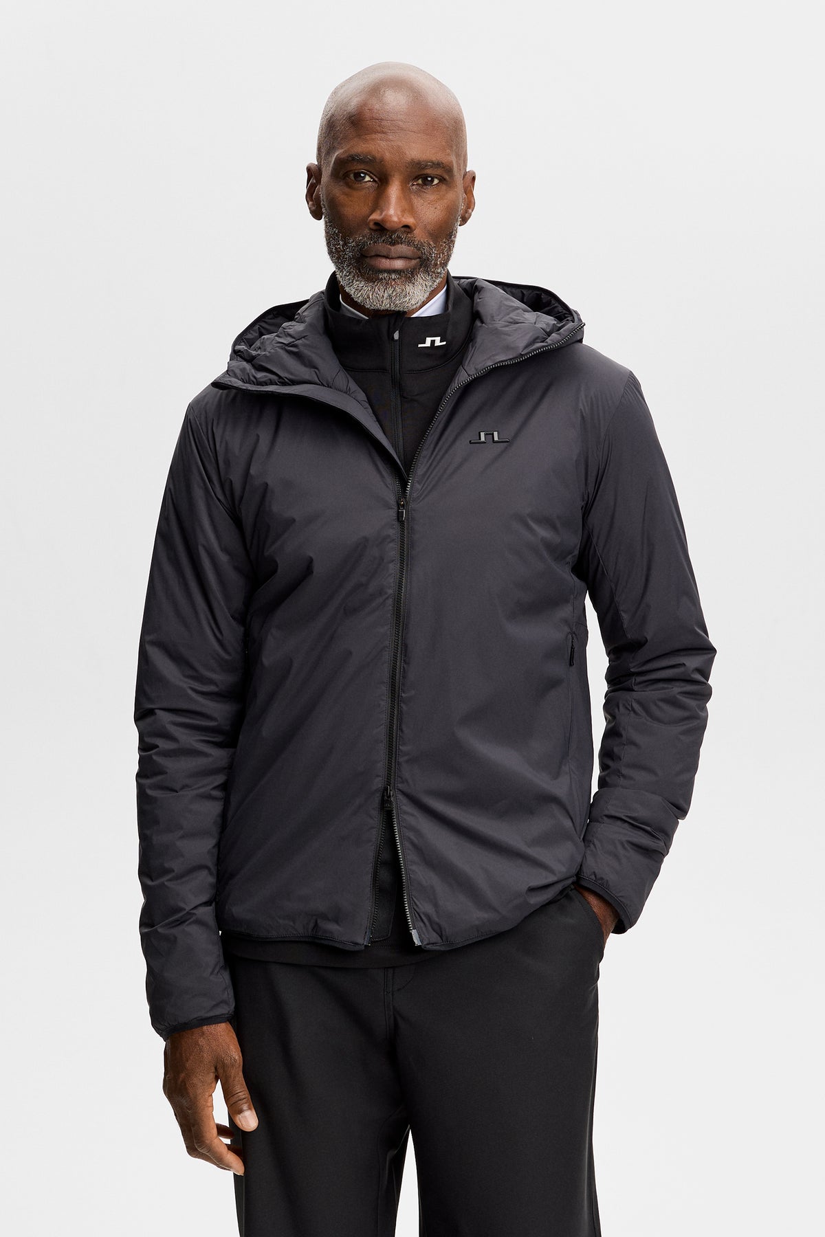 Model wearing the Clinton Hood jacket in black, front view with hood and Bridge logo at the chest.