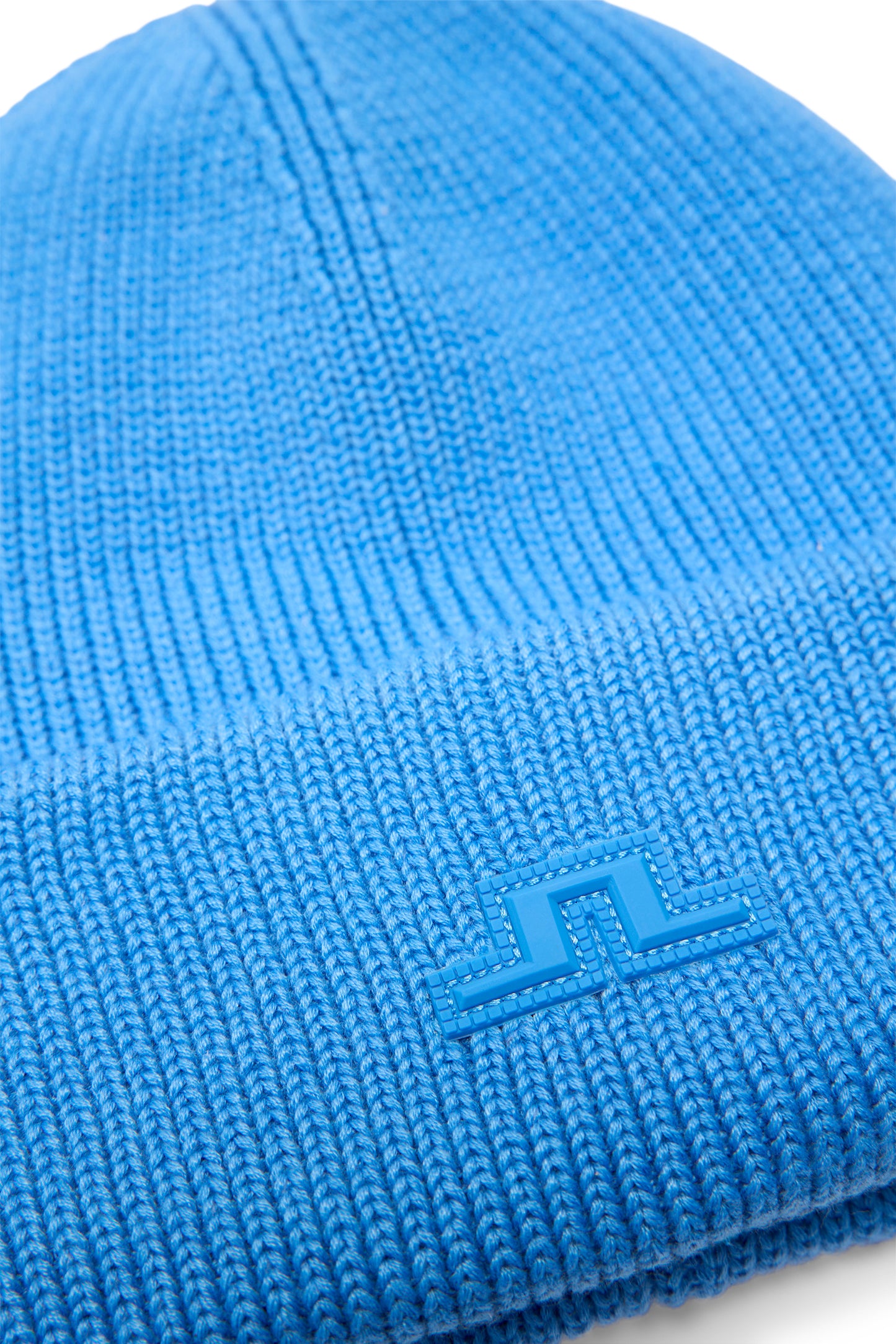 Detailansicht: Vale Beanie in Sonic Blue mit Rippstrick, Umschlagbündchen und gummiertem Bridge-Logo.