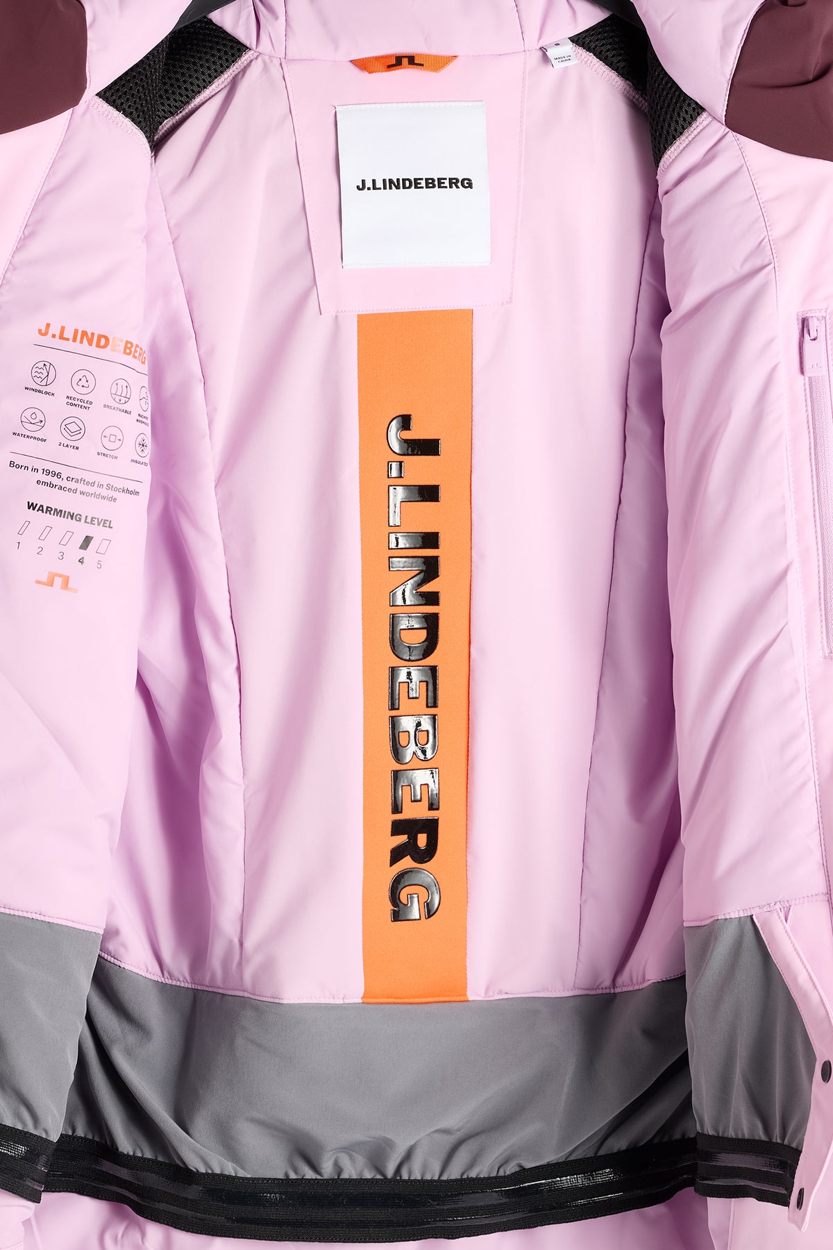 Nærbillede: Helia Jacket indvendigt med lyserødt for, orange J.LINDEBERG-stribe og integreret snefang.