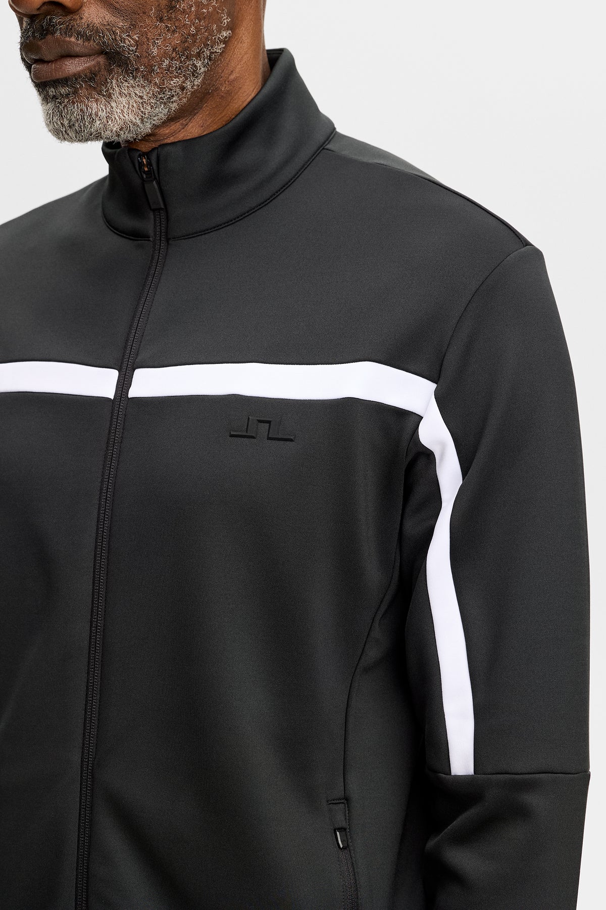 Gros plan : Sharpe Full Zip Mid Layer noir avec bande contrastante blanche et logo Bridge sur la poitrine.