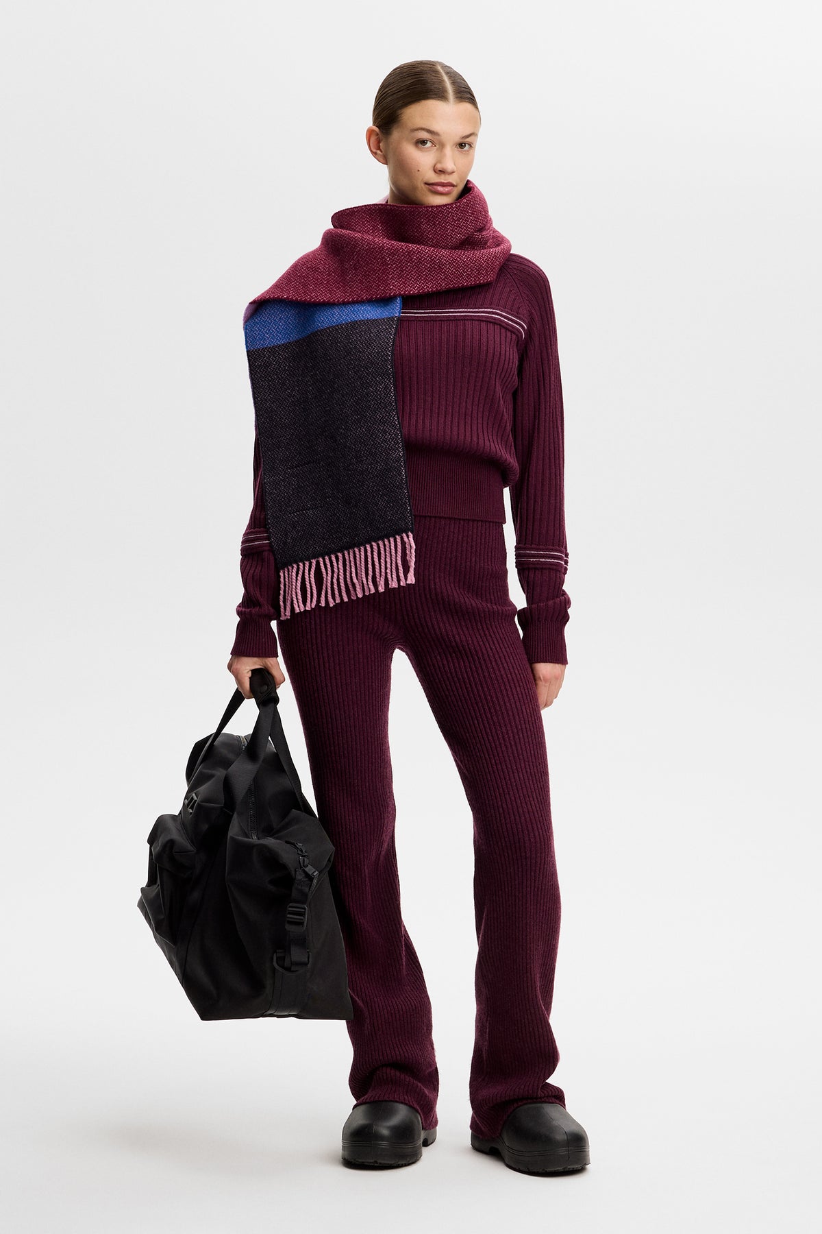 Helkropp framifrån: Hilda Knitted Rib Hoodie i Winetasting buren med matchande stickade byxor och halsduk.
