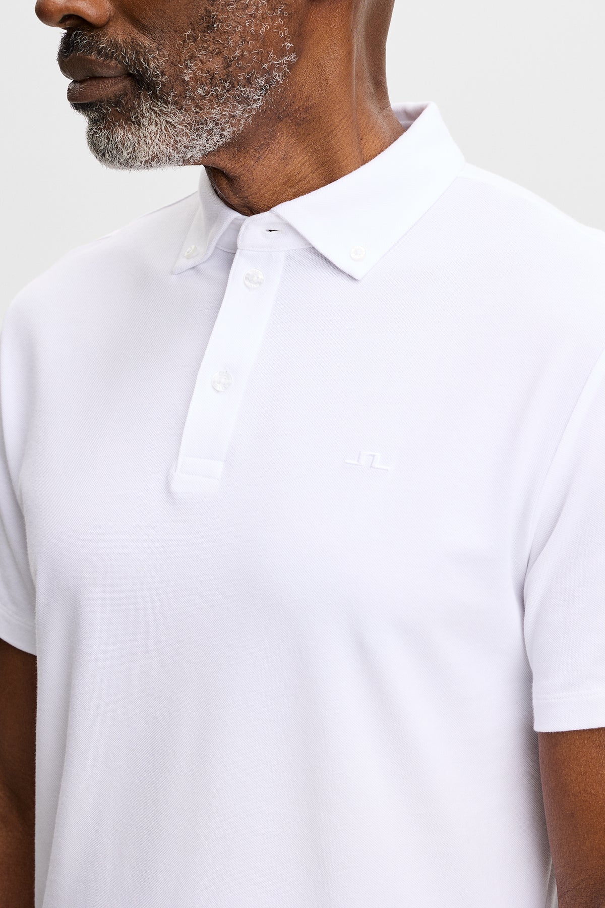 Close-up: Verse Button Down Polo in wit met button-downkraag, knoopsluiting en Bridge-logo op de borst.