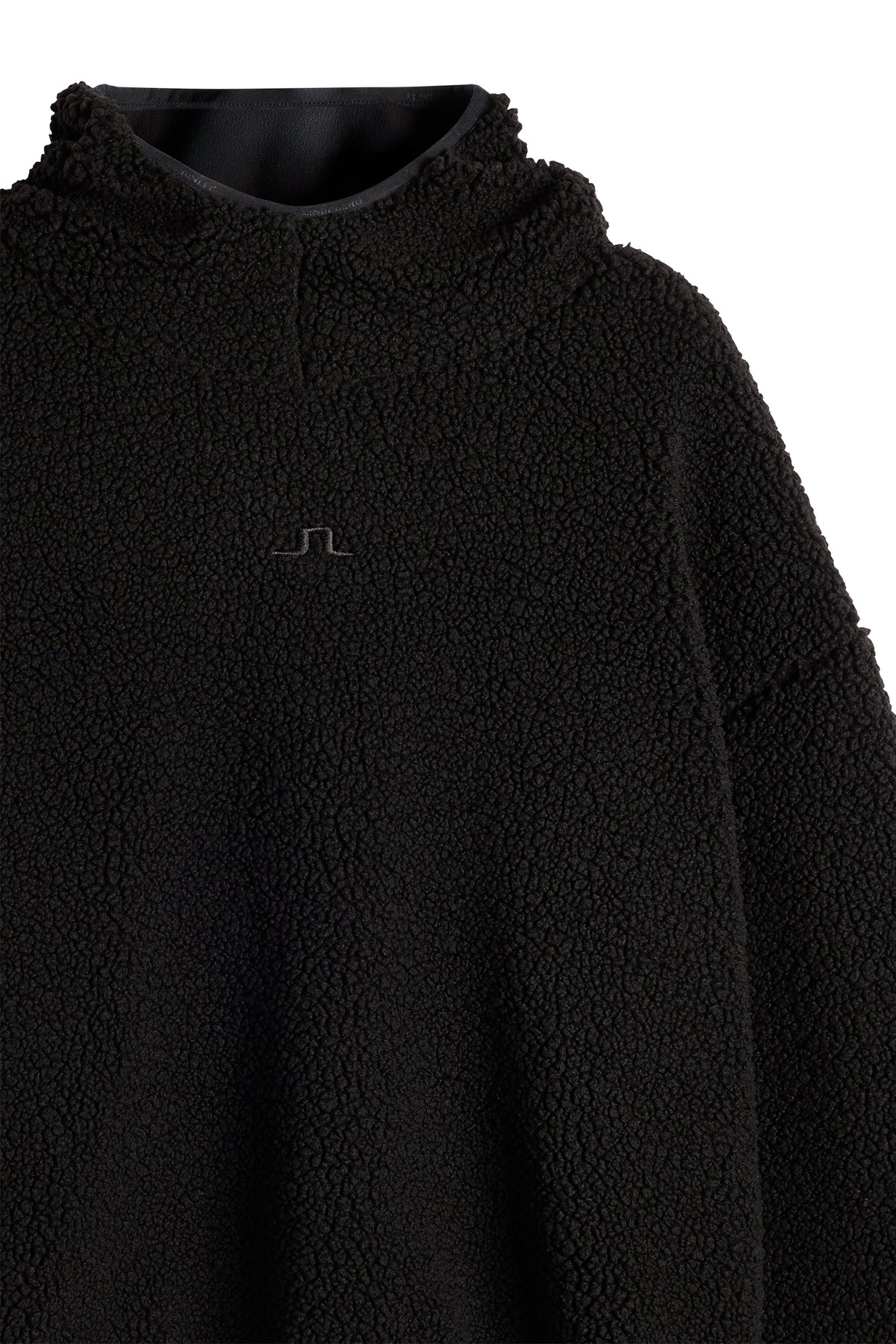 Detailansicht: Schwarzer Comona Pile Hood aus Teddy-Fleece mit tonalem Bridge-Logo auf der Brust.
