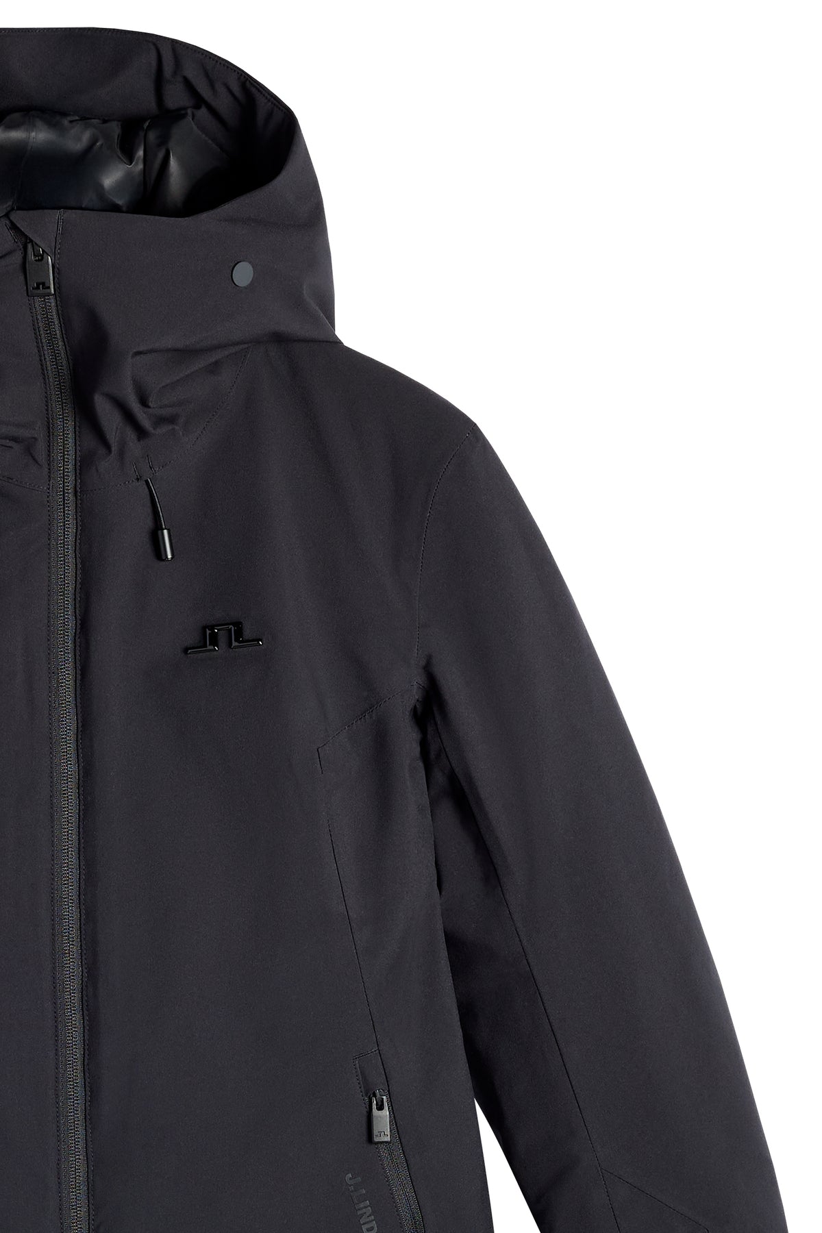 Nærbillede: Sort Lilia Jacket med hætte, gennemgående lynlås, lynlåslomme og Bridge-logo på brystet.