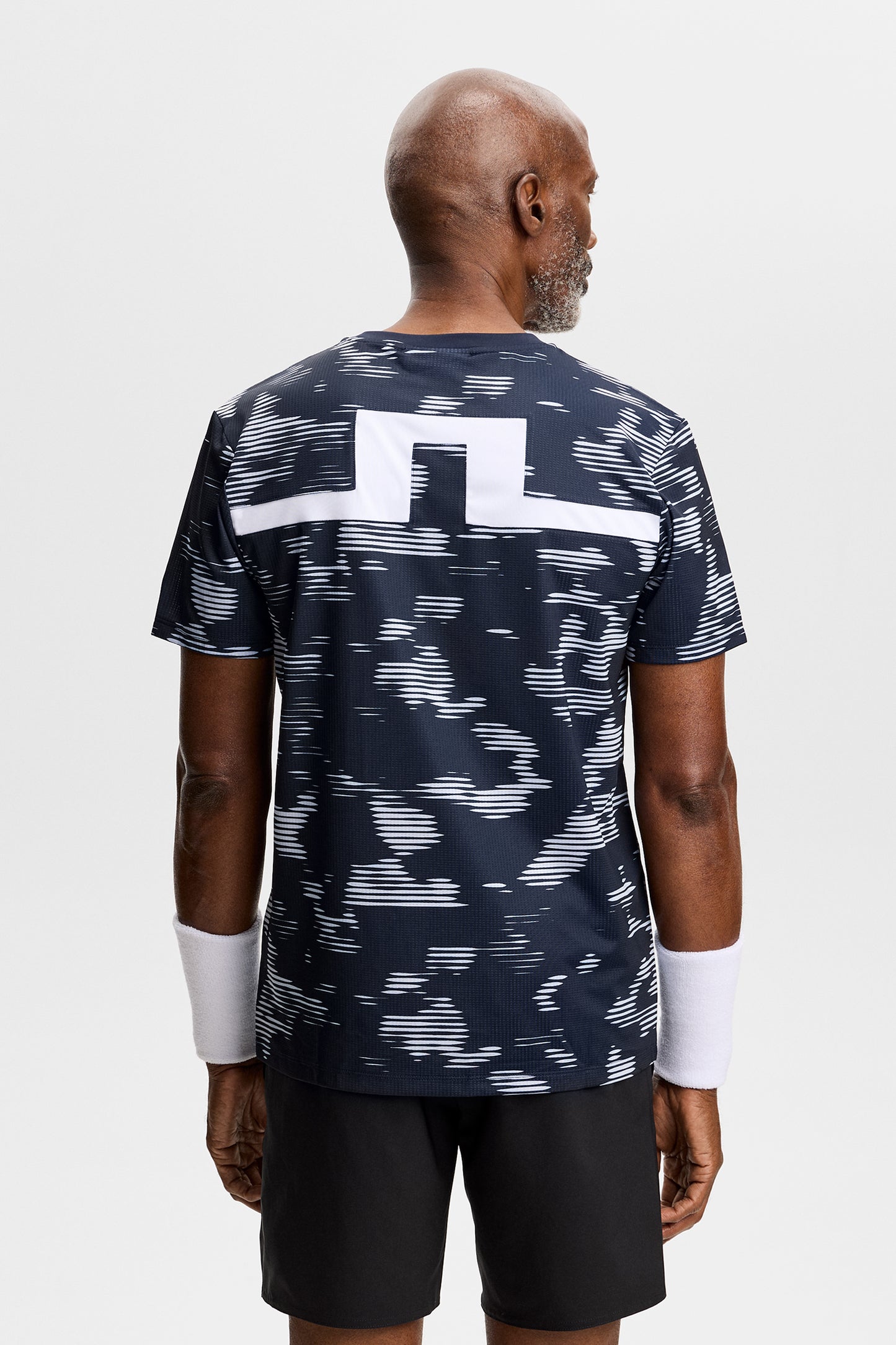 Achteraanzicht: Model draagt het Josip Printed T-shirt met all-over print en wit Bridge-inzetstuk op de rug.