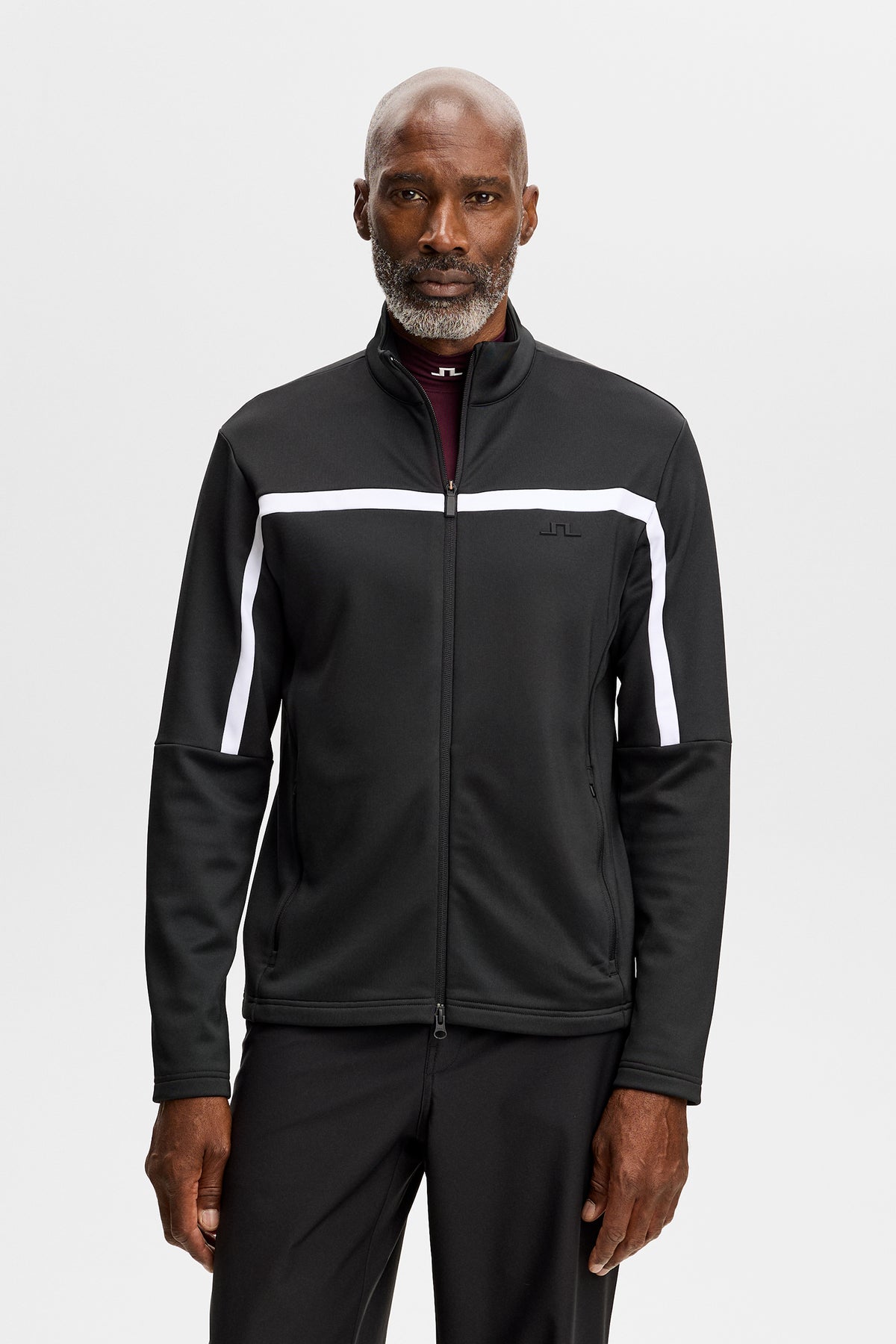 Vue de face : Sharpe Full Zip Mid Layer noir à col montant, bande blanche sur la poitrine et logo Bridge.