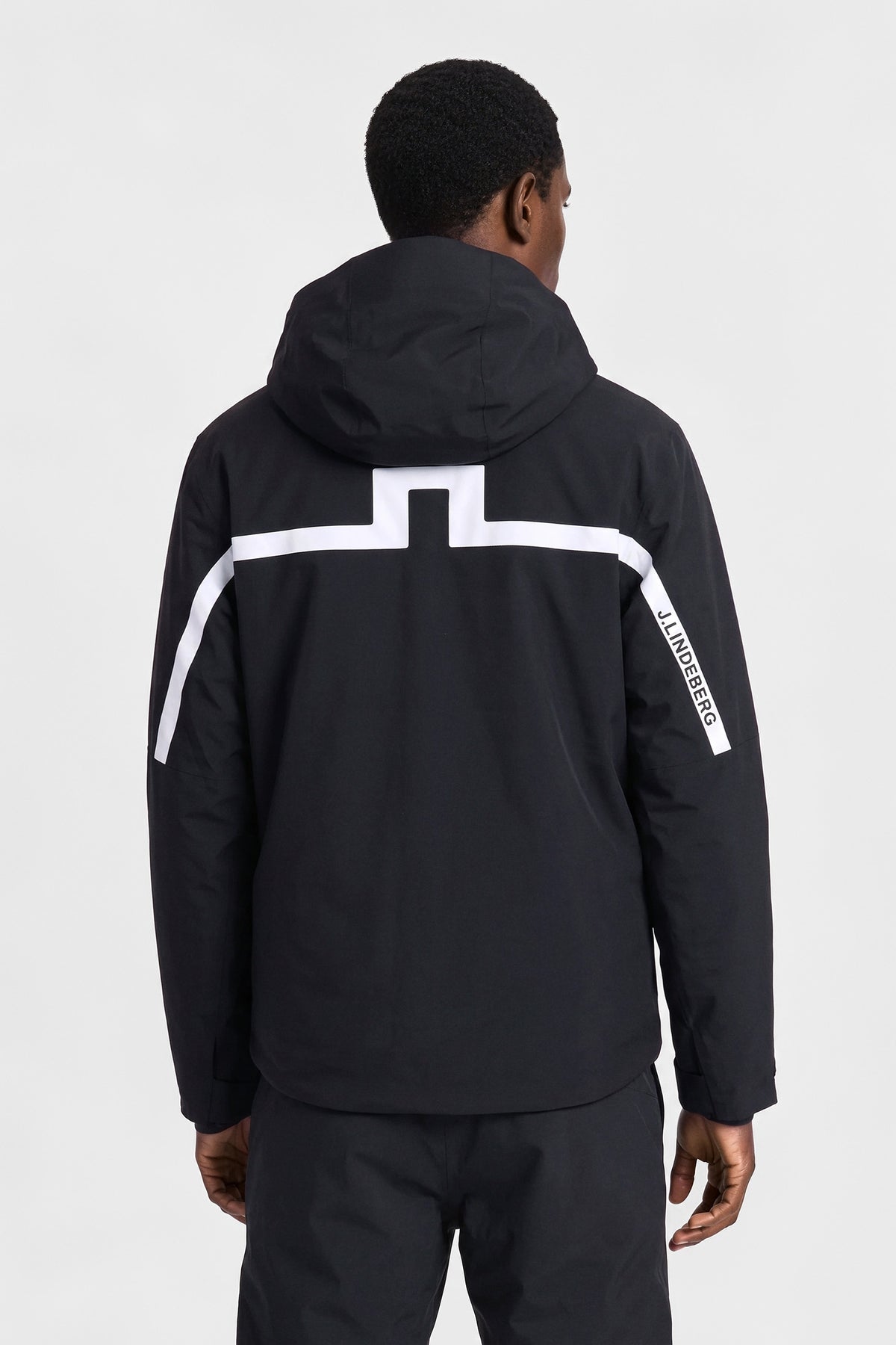 Back view: Black Windsor Jacket with hood and contrasting white Bridge logo across the back.