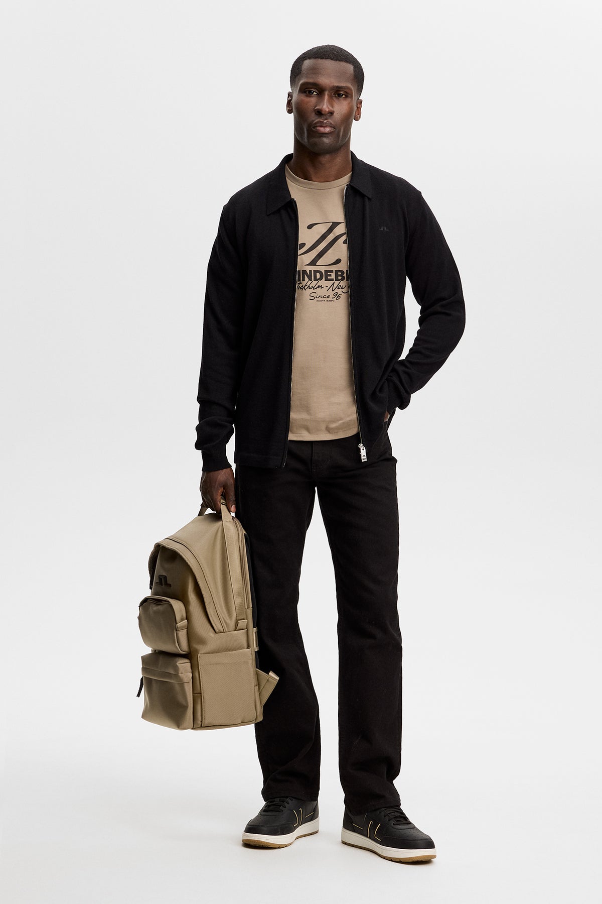 Model wearing the brindle Alpha Graphic T-shirt with a chest graphic, layered under a black zip jacket in a studio.