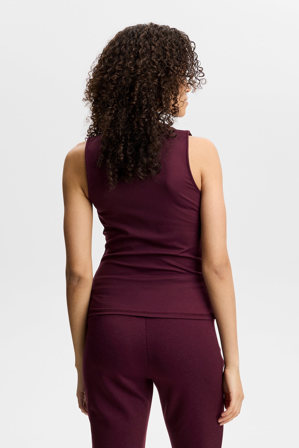Set bagfra: Vinrød Hannah Sleeveless Top med ærmeløst snit og ribbet struktur på en model.