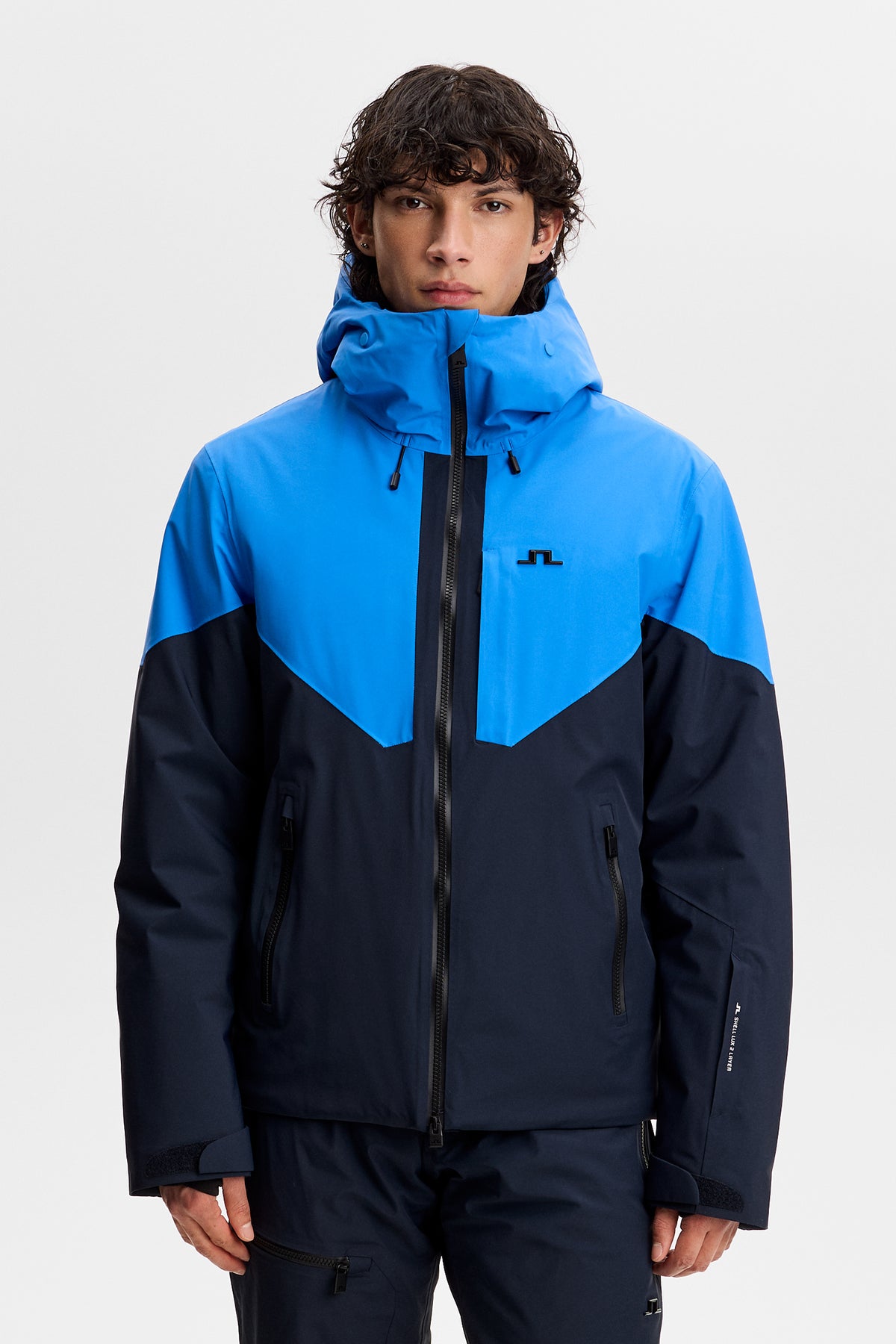 Vorderansicht: Caldwell Jacket in Sonic Blue im Colorblock-Design mit Kapuze, Frontreißverschluss und Bridge-Logo auf der Brust.