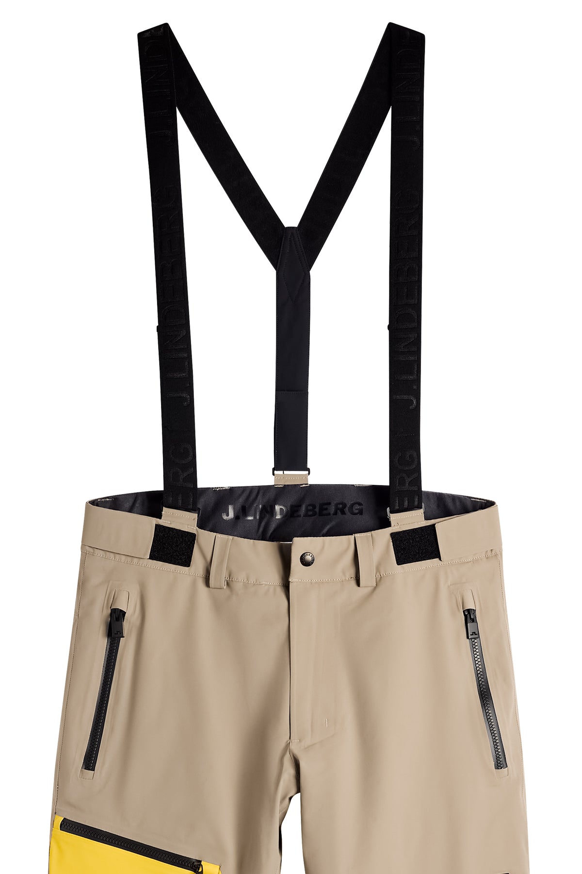 Gros plan : Crue Suspender Blocked Pant beige avec bretelles noires logotées et poches avant zippées.