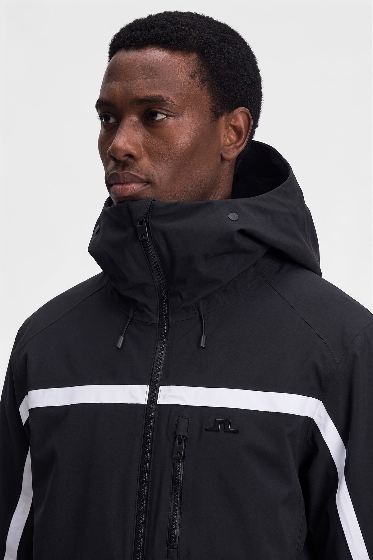 Close-up of the black Windsor Jacket featuring the high collar, hood, and chest Bridge logo.