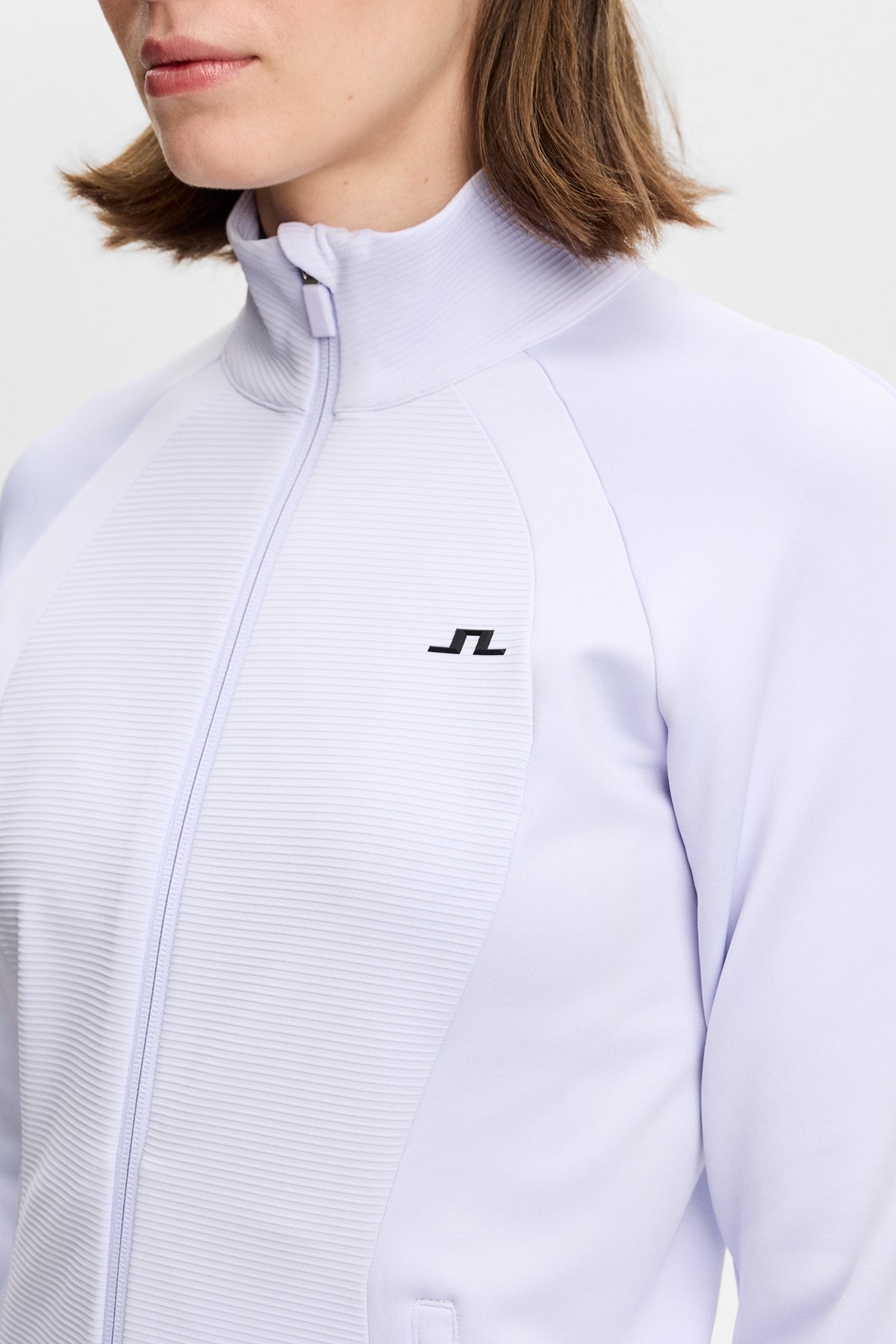 Close-up: Mireya Full Zip Mid Layer in Purple Heather met geribd voorpand, ritssluiting en Bridge-logo op de borst.