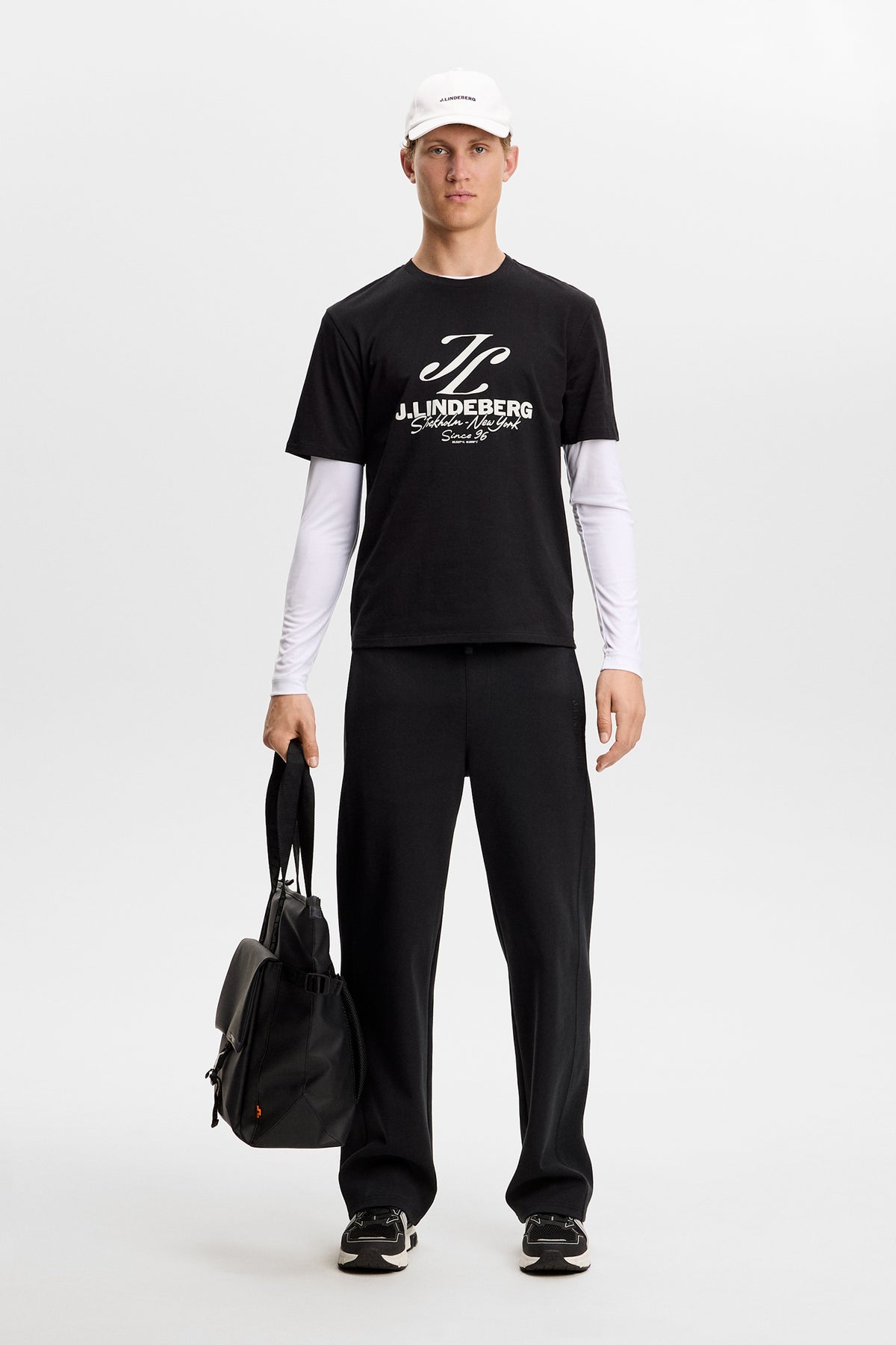 Model wearing the black Alpha Graphic T-shirt featuring a white chest graphic, layered over a long-sleeve top.