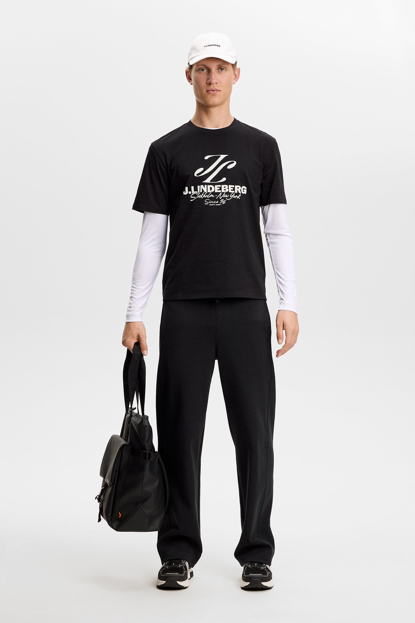 Model wearing the black Alpha Graphic T-shirt featuring a white chest graphic, layered over a long-sleeve top.