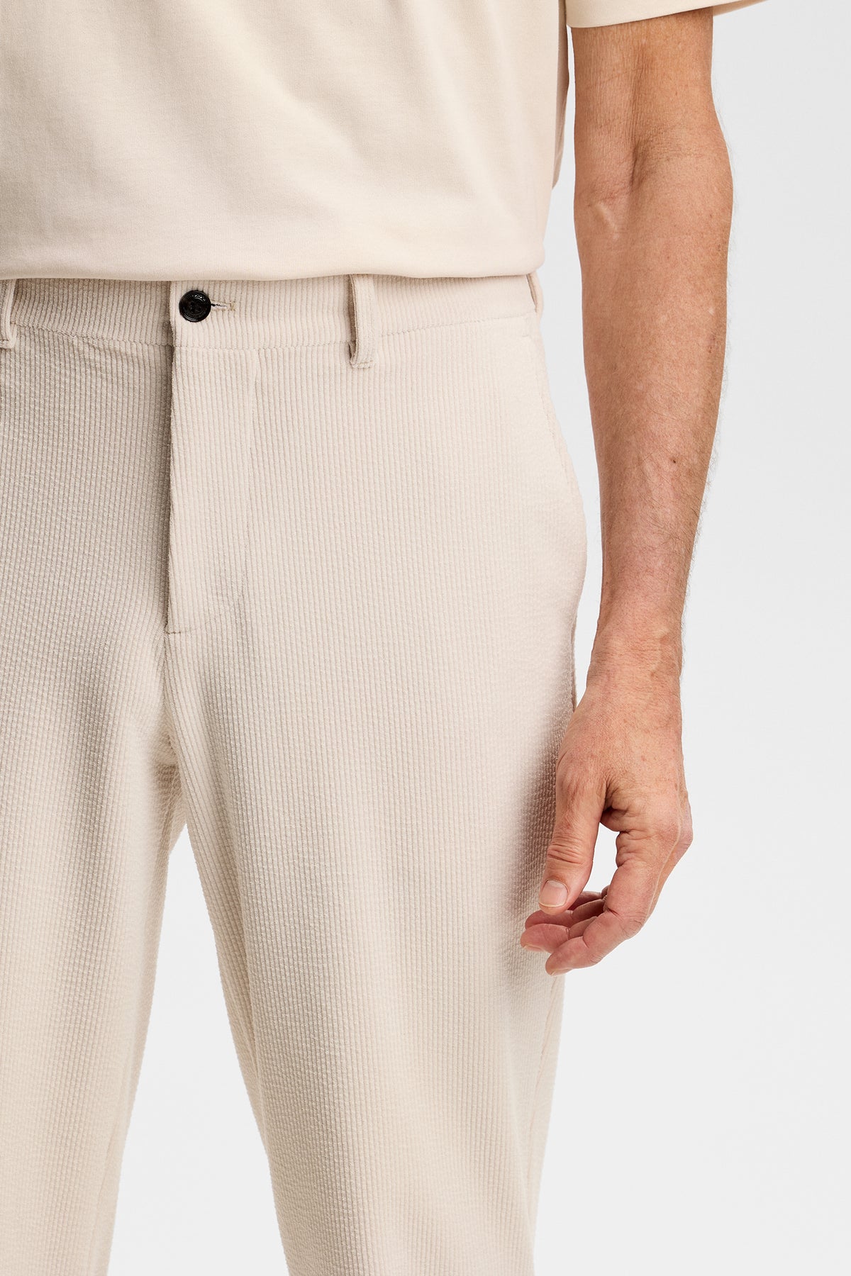 Närbild framifrån: Logan Drape Cord Pants i Moonbeam med ribbad manchesterstruktur, mörk knapp och sidoficka.