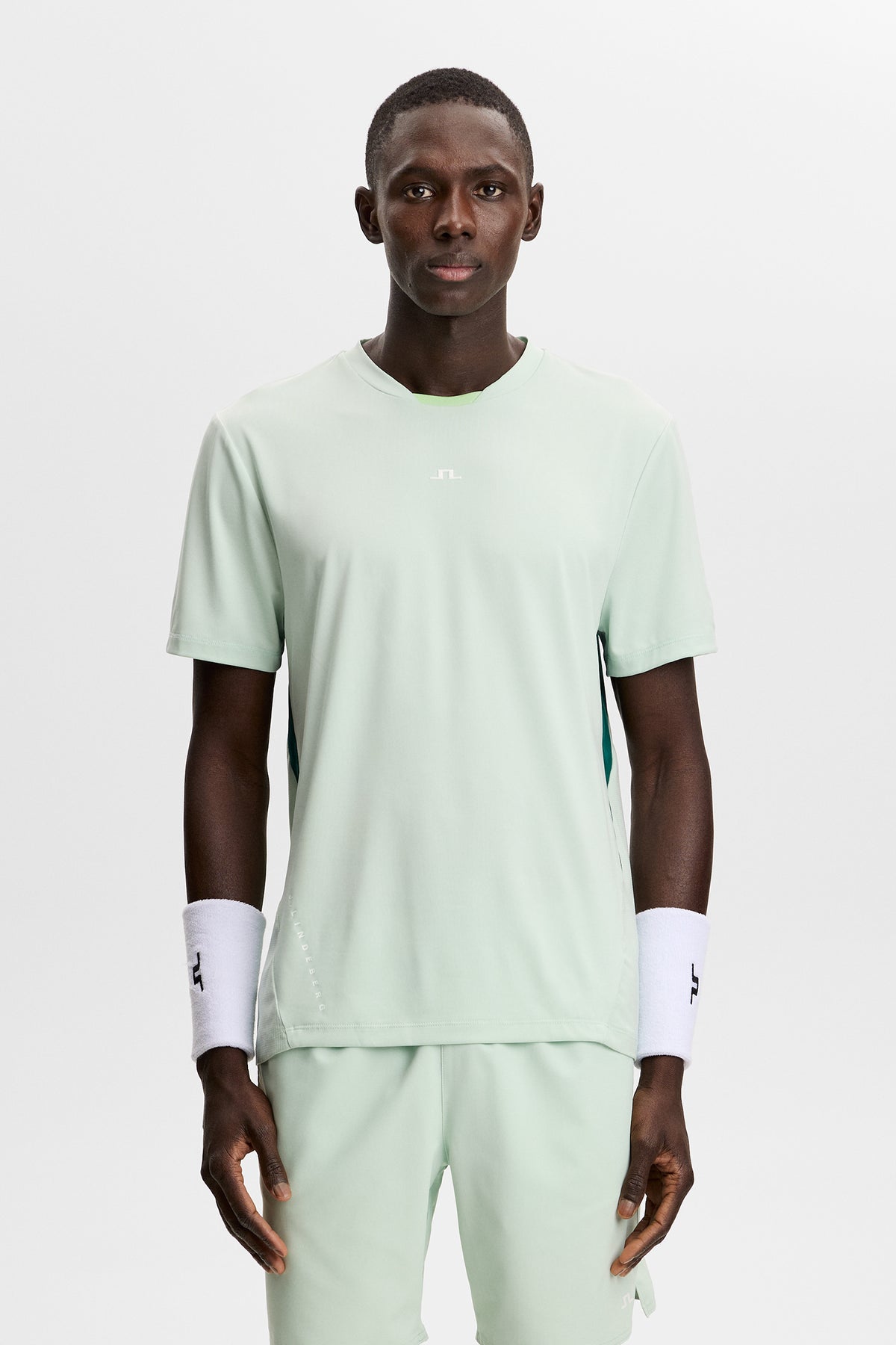 Model wearing the light green Dennis T-shirt with short sleeves and a central Bridge logo in a studio setting.
