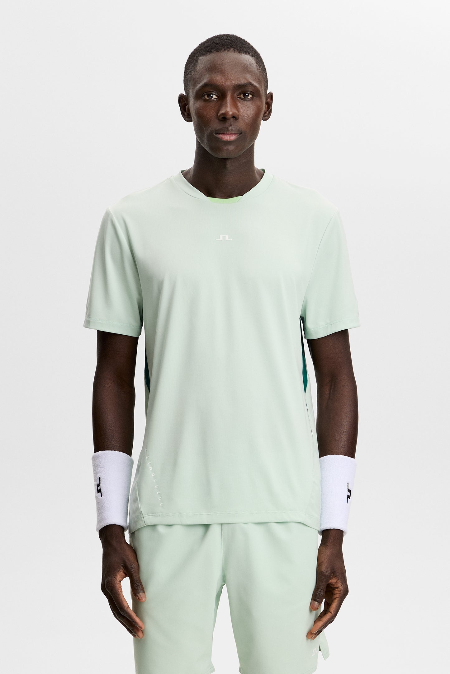 Model wearing the light green Dennis T-shirt with short sleeves and a central Bridge logo in a studio setting.