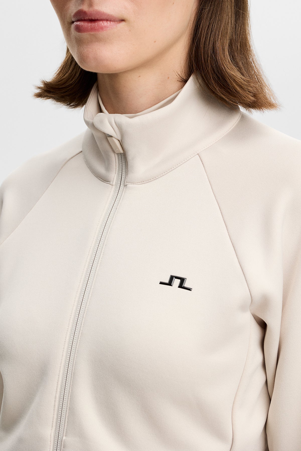 Close-up of the Portia Polartec Mid Layer in Moonbeam with high neck, zipper, and chest Bridge logo.