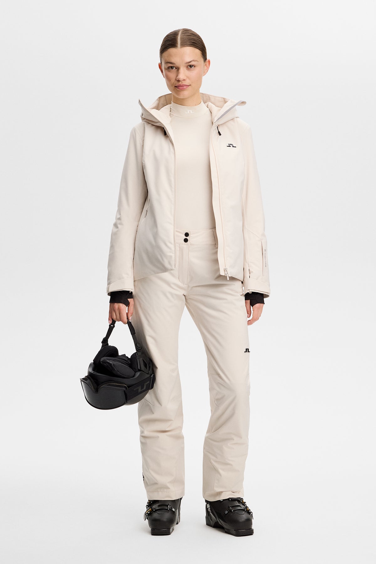 Vorderansicht: Moeva Pant in Moonbeam mit Bridge-Logo am Bein, getragen mit Skijacke und Skischuhen.