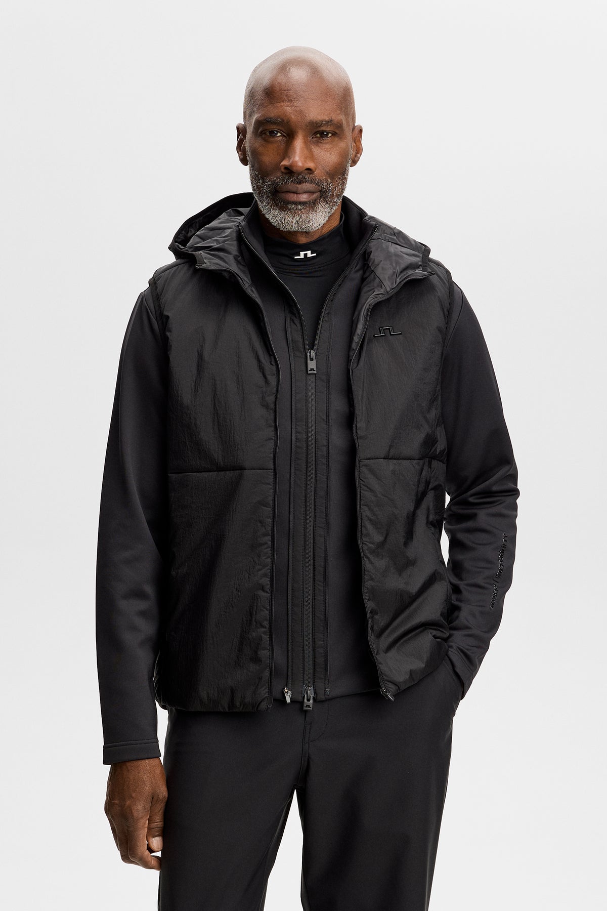 Vorderansicht: M Solarcore 3 in 1 Jacket in Schwarz mit Reißverschluss, Kapuze und Bridge-Logo auf der Brust.