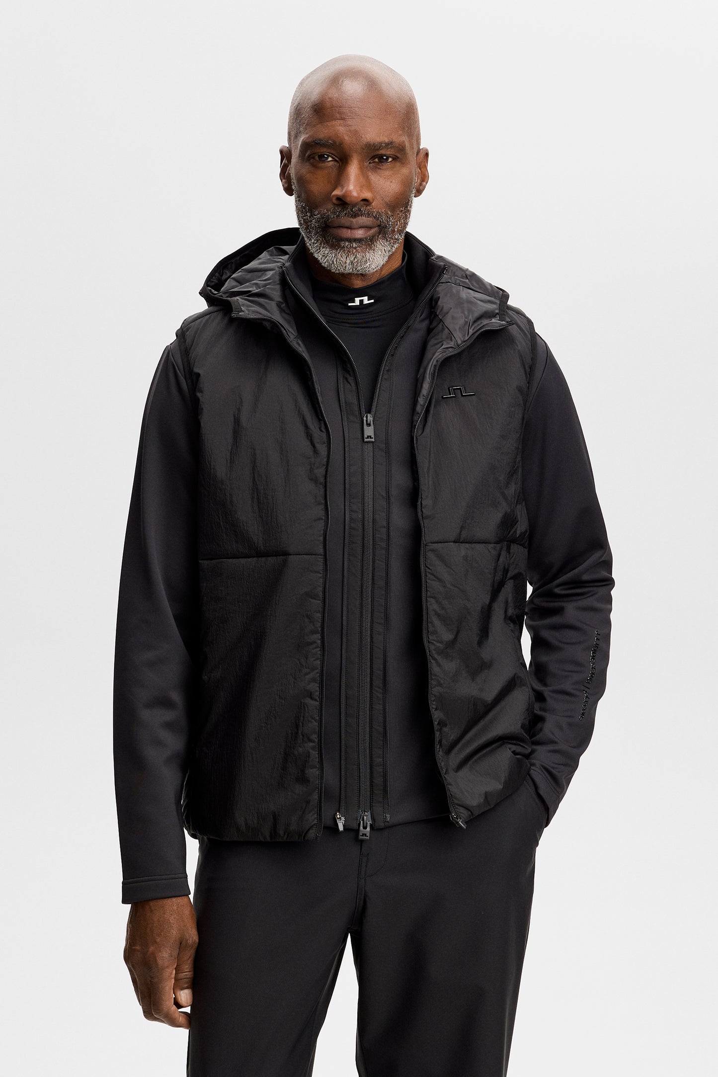 Vorderansicht: M Solarcore 3 in 1 Jacket in Schwarz mit Reißverschluss, Kapuze und Bridge-Logo auf der Brust.