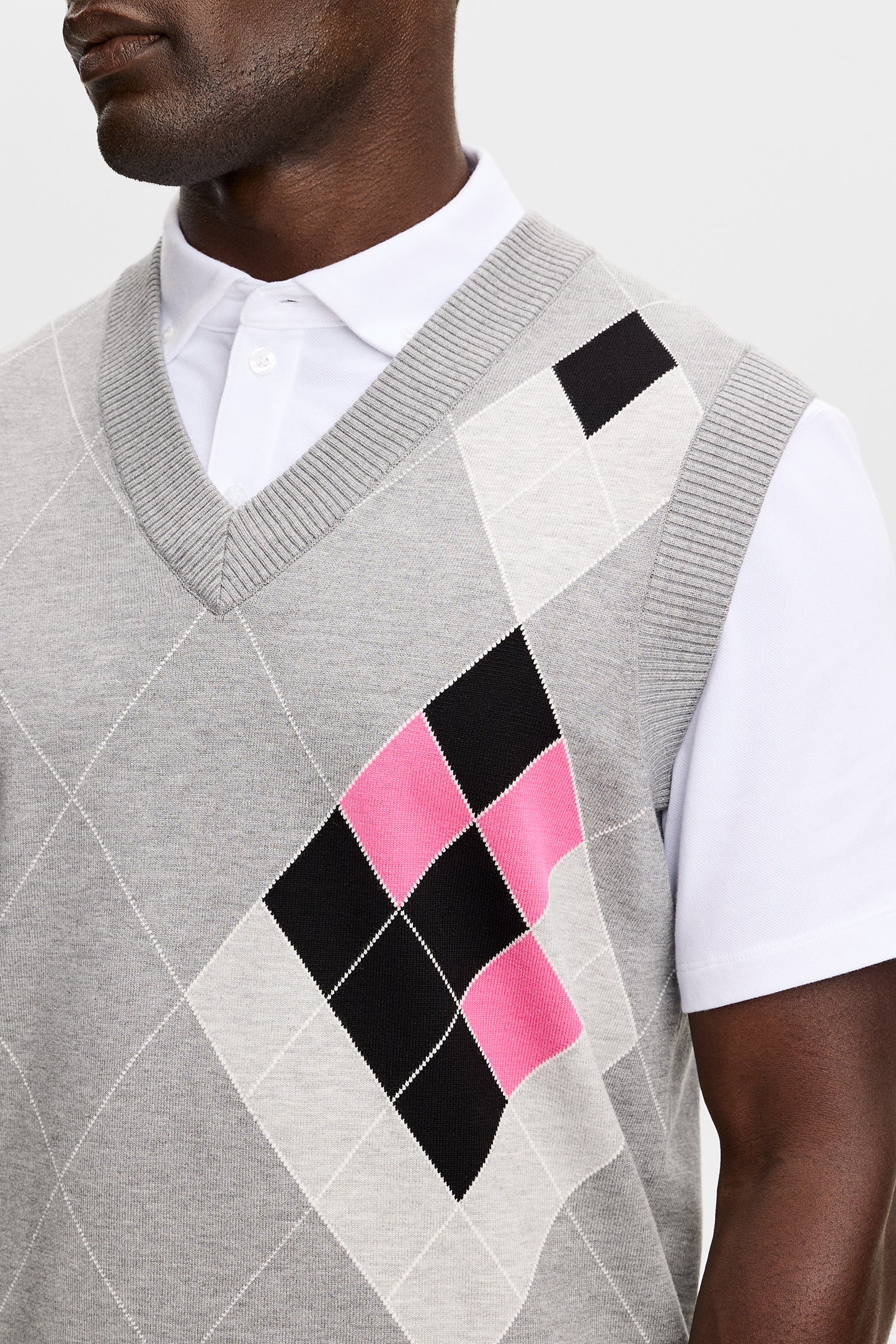 Gros plan : Anton Argyle Knit Vest gris avec motif à losanges rose et noir et col en V côtelé.