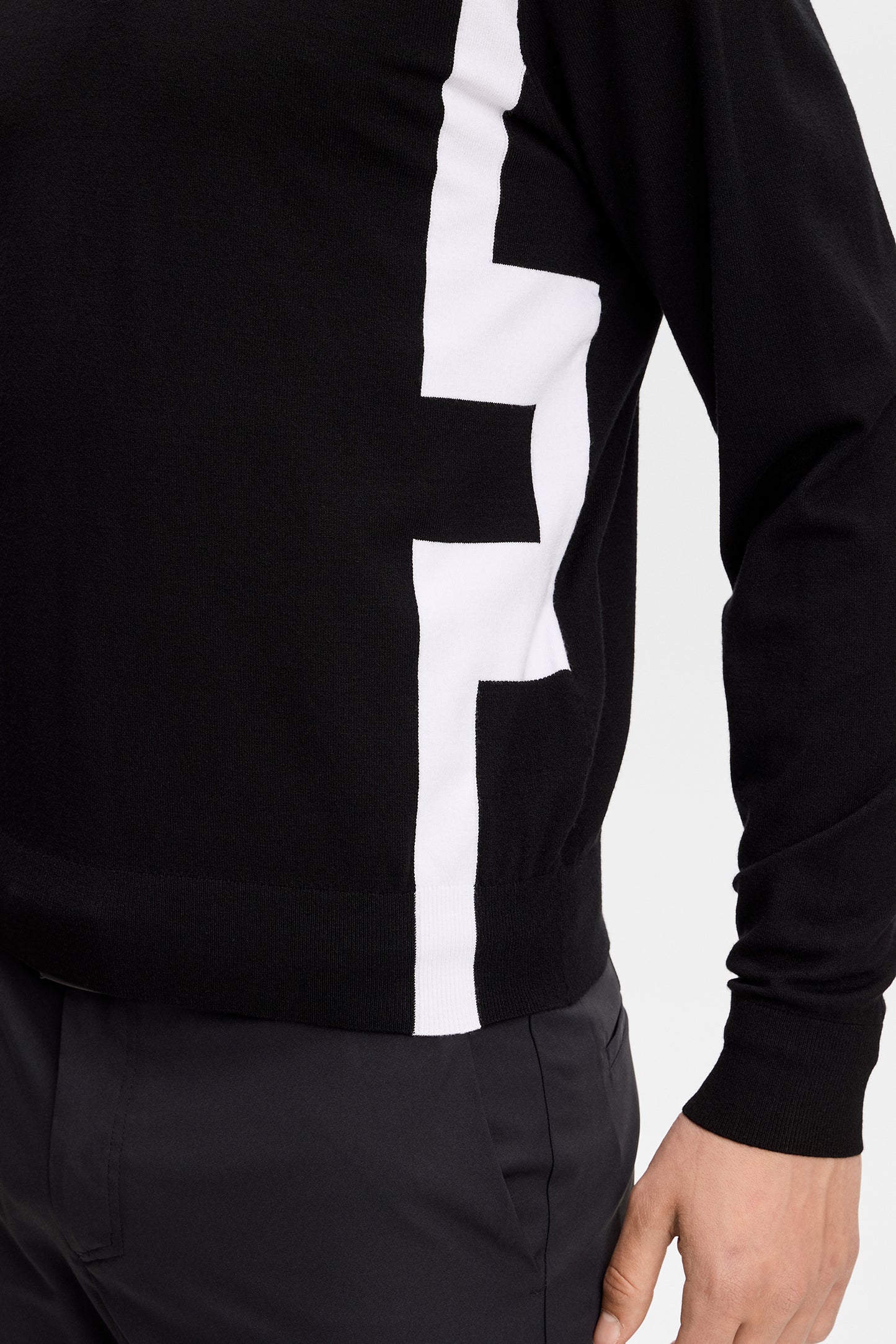 Nahaufnahme: Schwarzer Kendrick Knitted Zip Sweater mit weißer Bridge-Logo-Intarsie an der Seite.