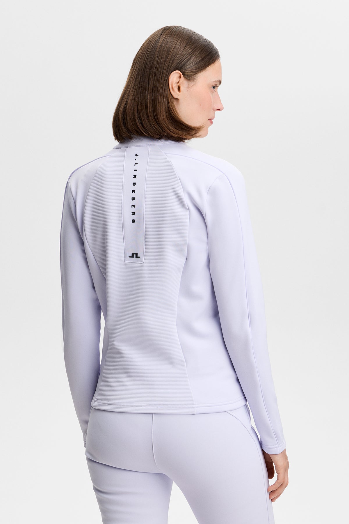 Achteraanzicht: Model draagt de Mireya Full Zip Mid Layer in Purple Heather met geribd achterpand en J.LINDEBERG-print.