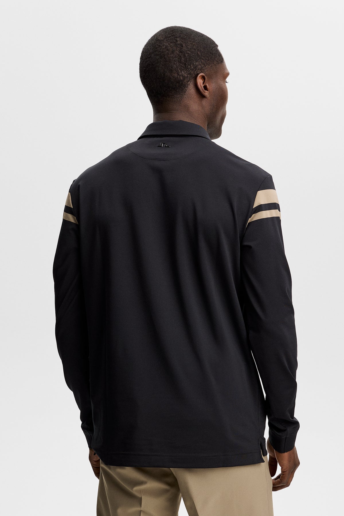 Kenny LS stripe polo in black, back view on model showing tan sleeve stripes and Bridge logo on the neck.