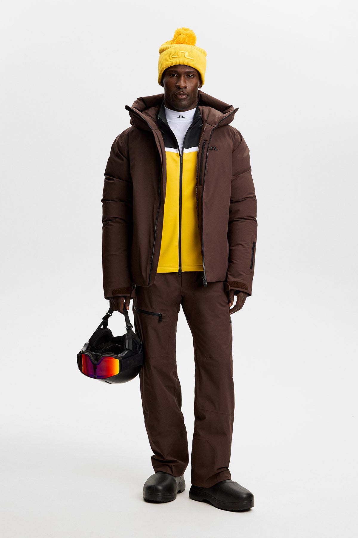 Vue de face : Sharpe Full Zip Mid Layer jaune porté sous une veste marron, avec bonnet jaune et casque de ski.