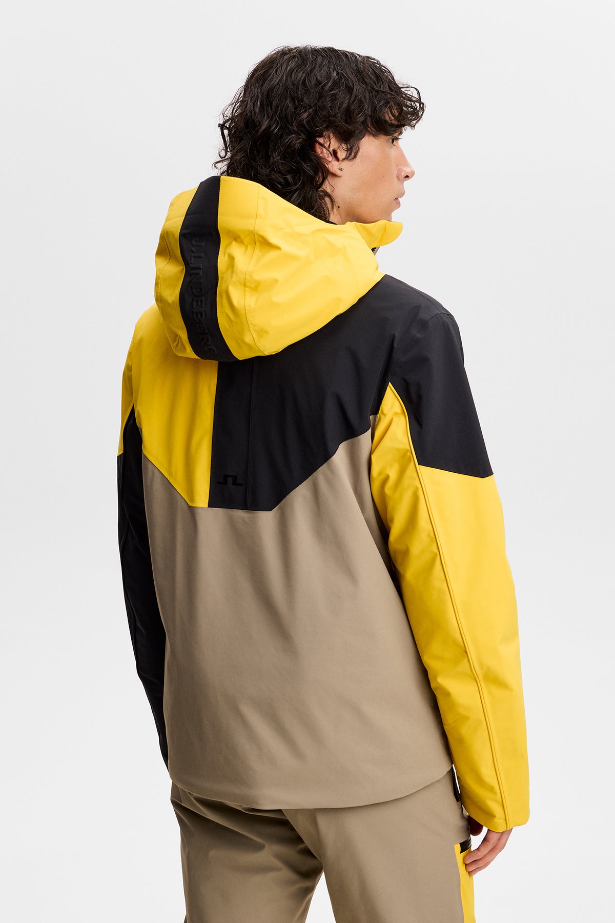 Set bagfra: Caldwell Jacket i Bumblebee med farveblokke, hætte og Bridge-logo på ryggen.