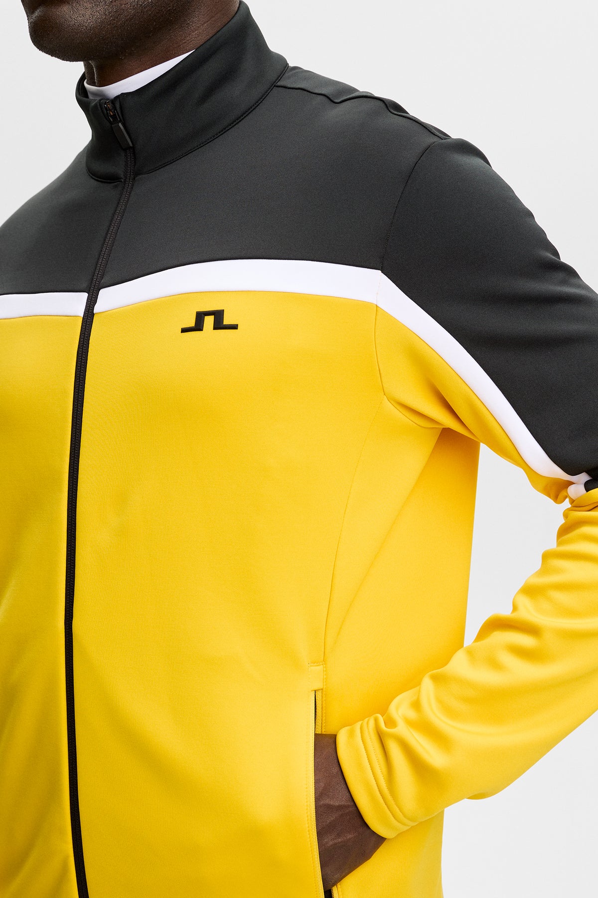 Gros plan : Sharpe Full Zip Mid Layer jaune et noir avec col montant et logo Bridge sur la poitrine.
