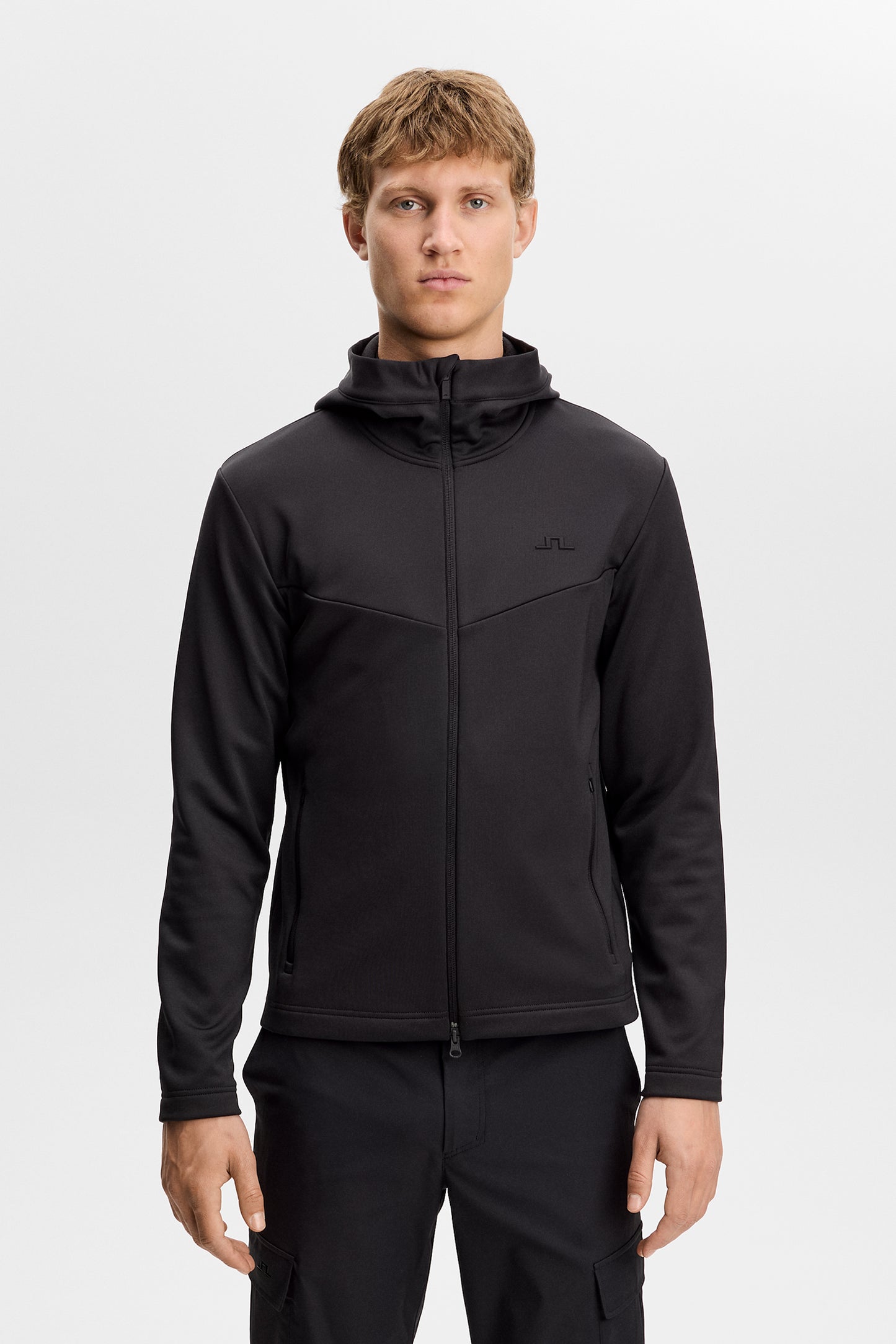 Maclean Zip Hood in black, front view on a model, featuring a full zip, hood, and tonal Bridge logo on the chest.
