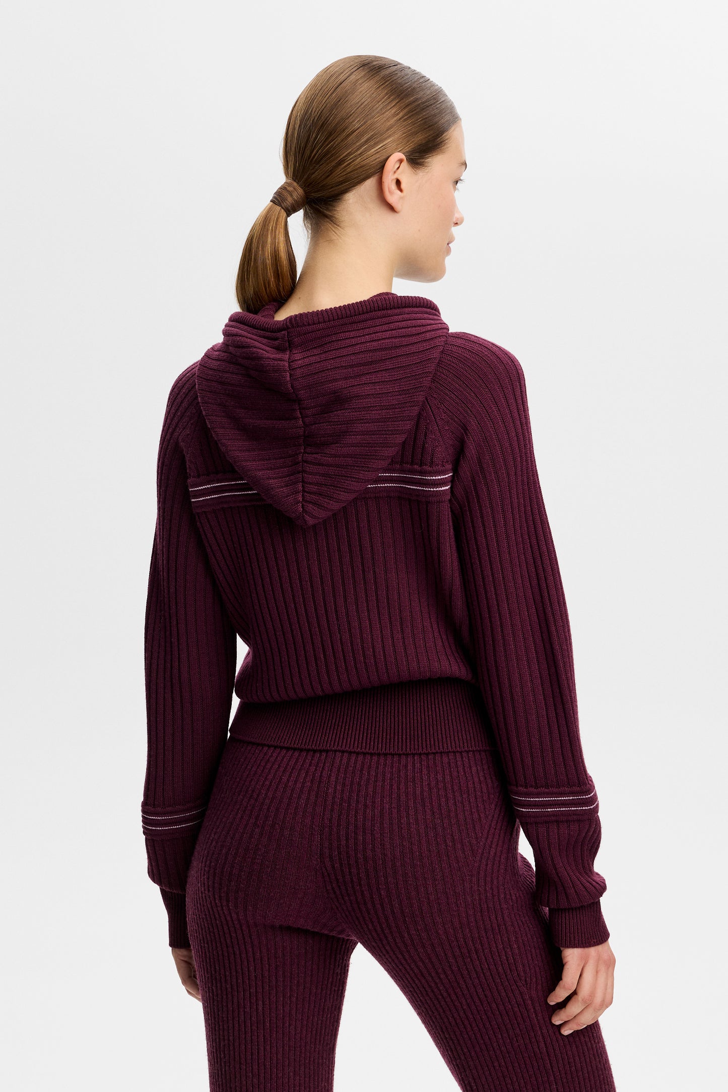 Bakifrån: Hilda Knitted Rib Hoodie i Winetasting med stickad huva, ribbad struktur och kontrasterande randdetaljer.