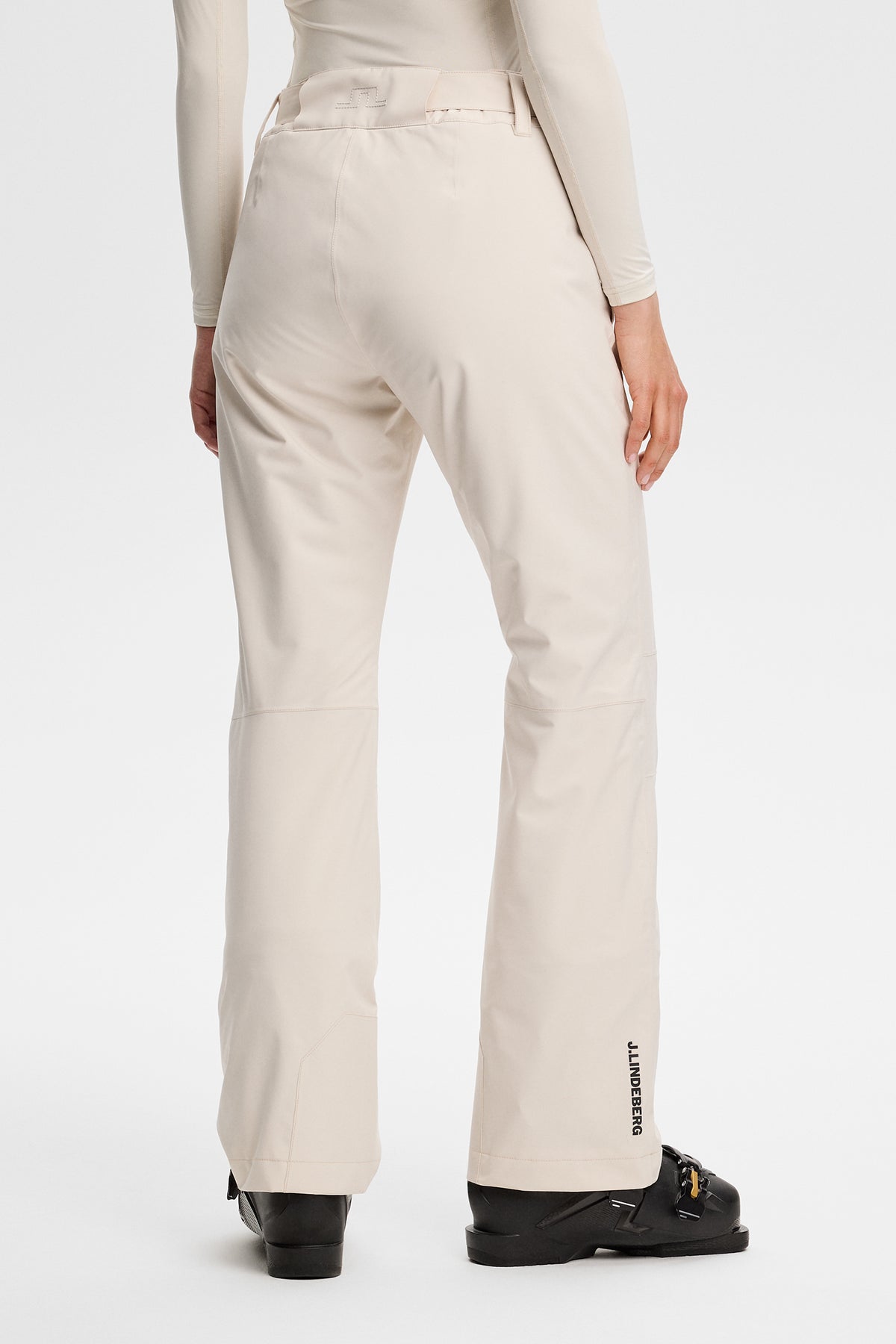 Rückansicht: Moeva Pant in Moonbeam mit Bridge-Logo am Bund und J.LINDEBERG-Schriftzug am Saum.