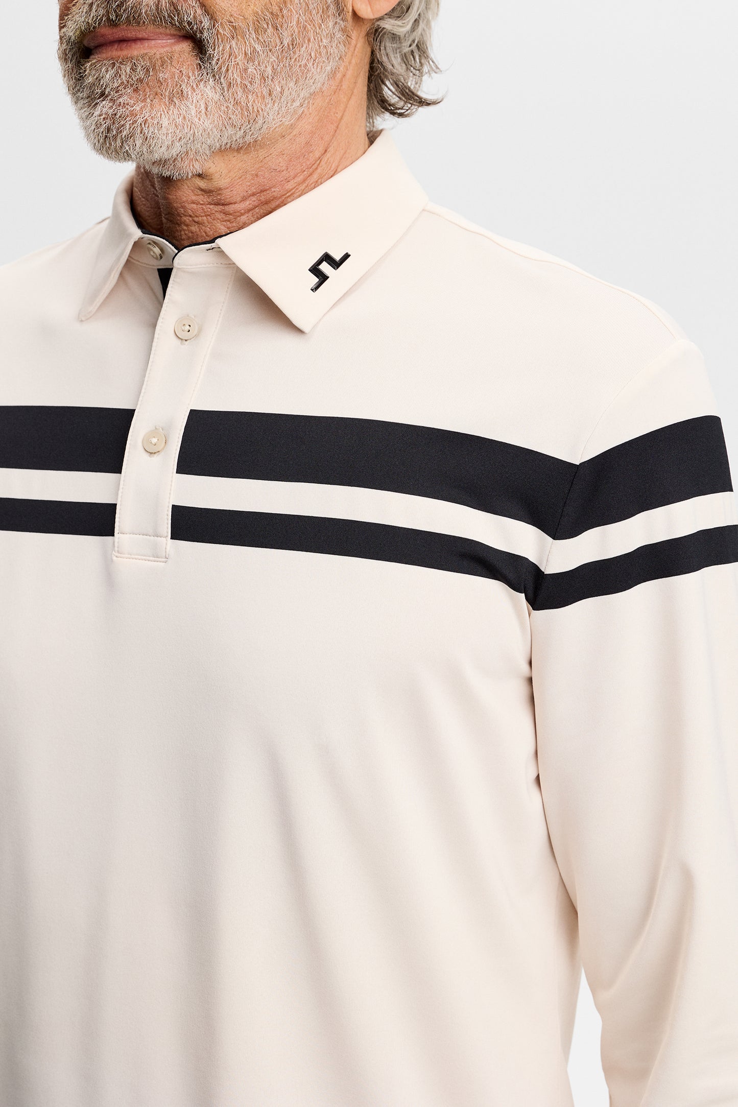 Close-up: Kenny LS stripe polo in cream with black chest stripes, polo collar, and Bridge logo on the collar.