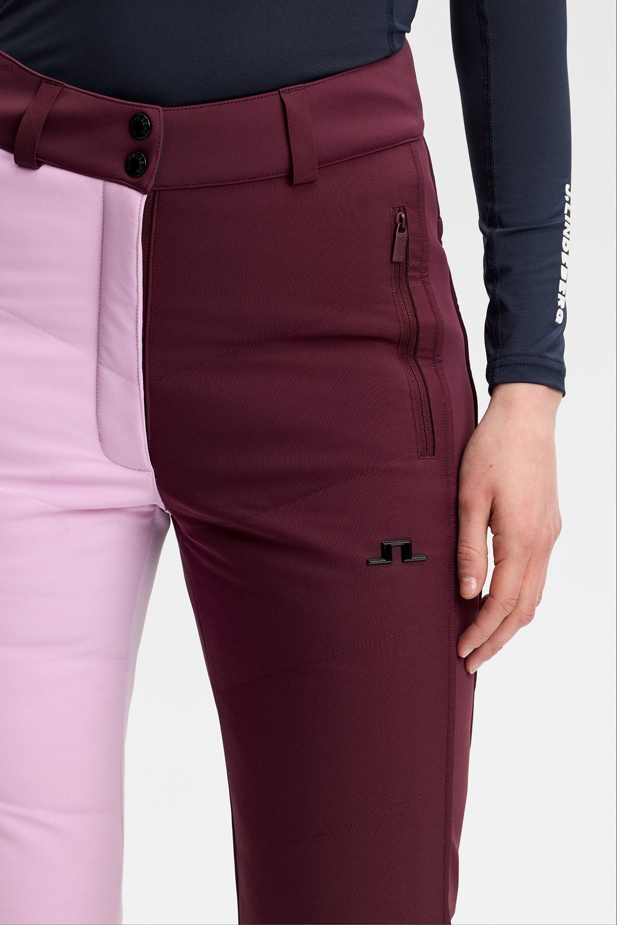 Detailansicht: Yara Blocked Down Pant in Winetasting mit Colorblocking, Reißverschlusstasche und Bridge-Logo am Bein.