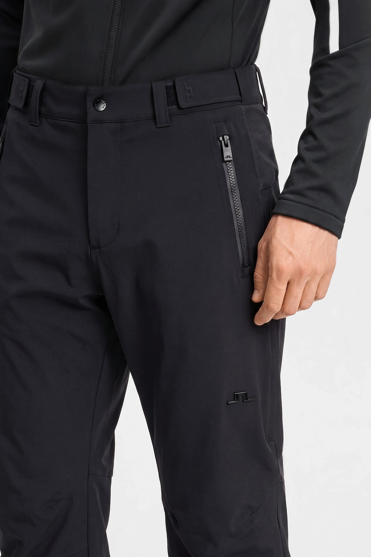 Close-up of the black Whitman Pant showing the waistband, zippered pocket, and tonal Bridge logo.