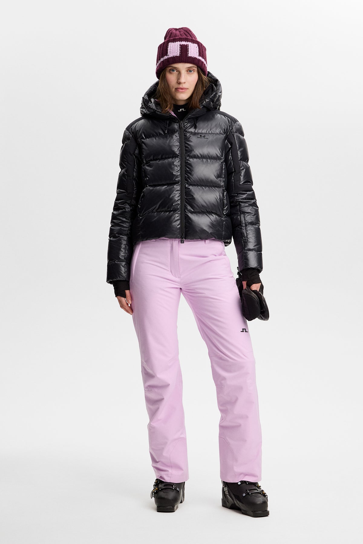 Vorderansicht: Moeva Pant in Orchid Bouquet an einem Model, kombiniert mit schwarzer Steppjacke und Skischuhen.
