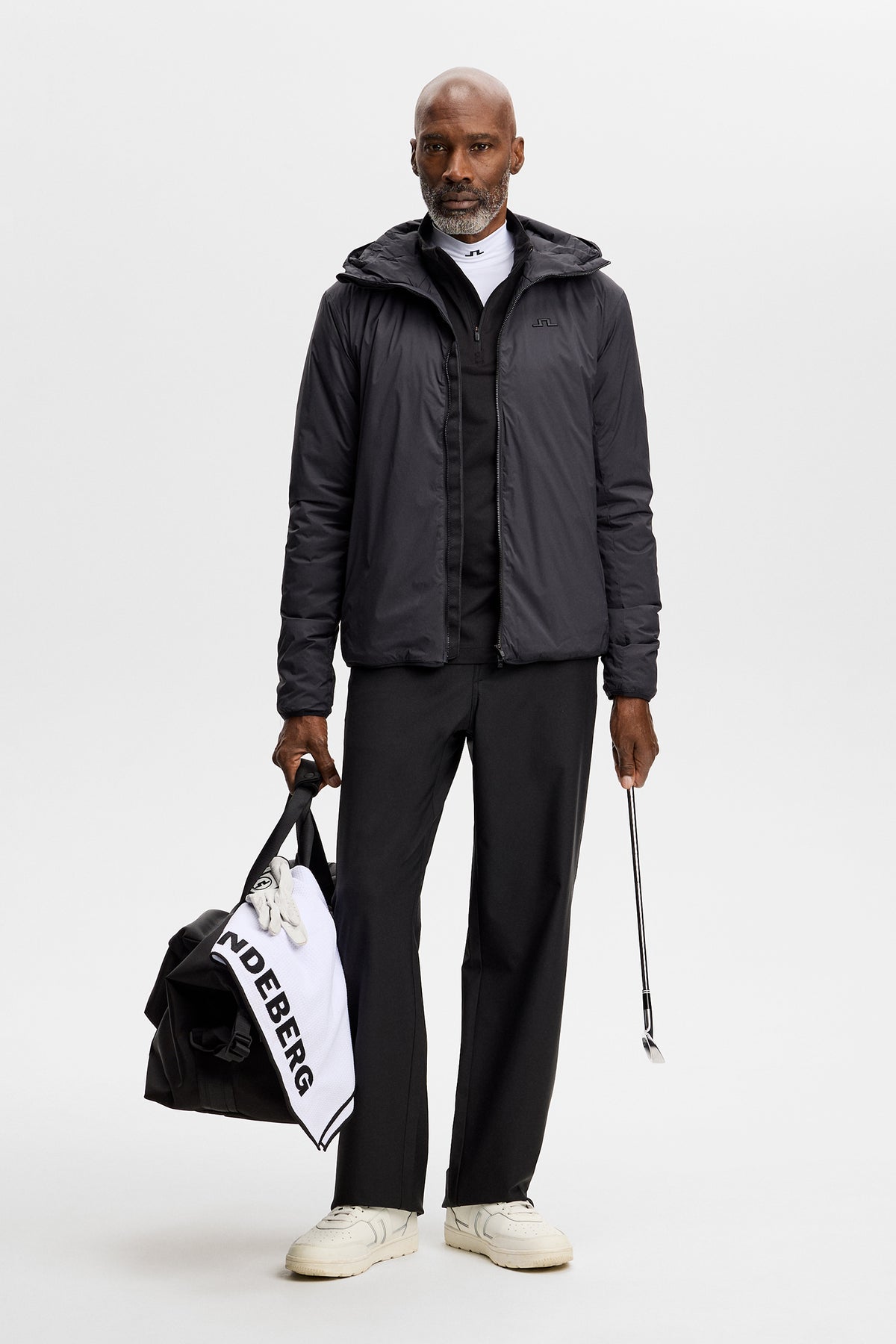Model wearing the black Clinton Hood jacket with front zip in a full-body studio shot.
