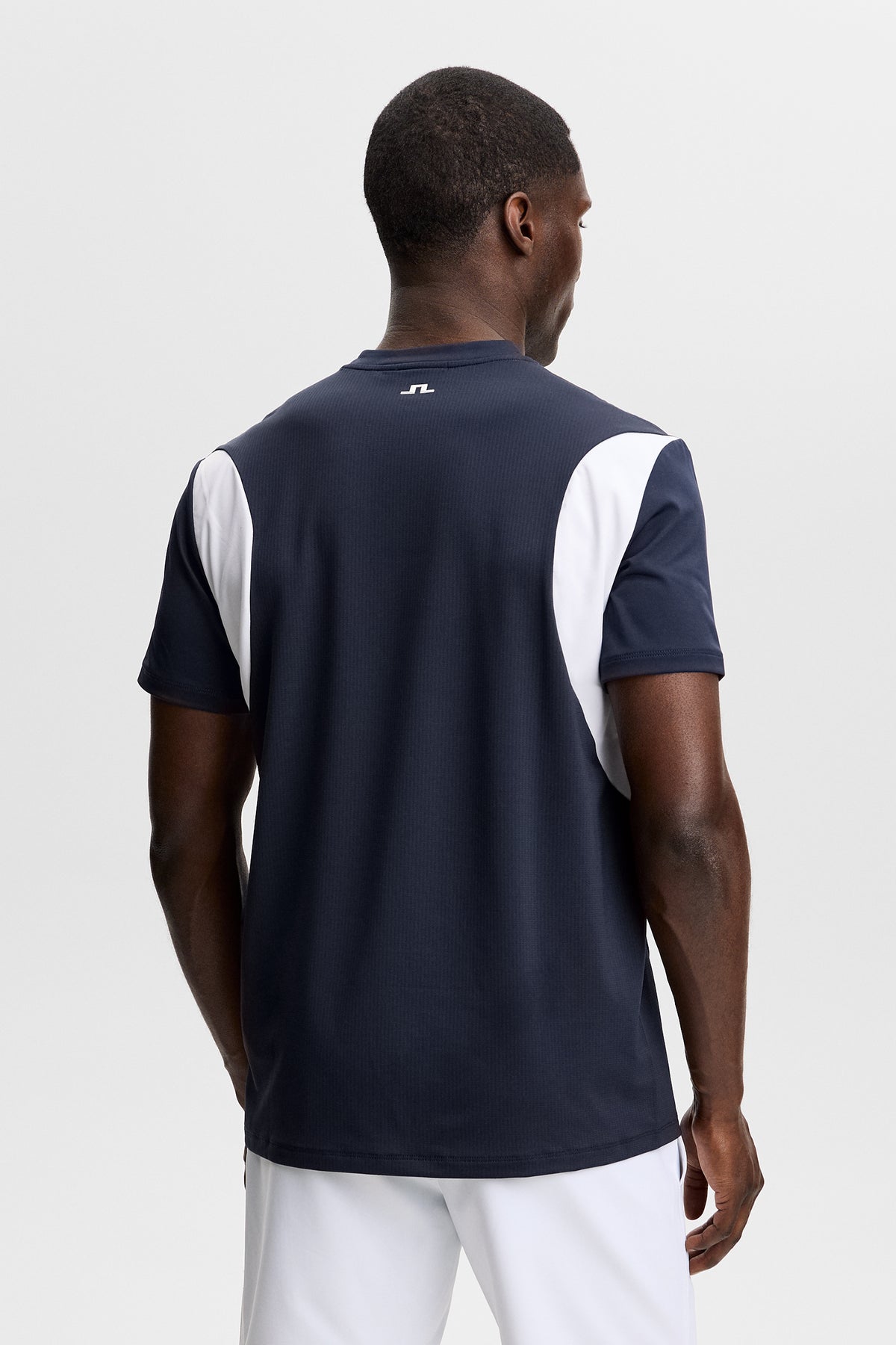 Set bagfra: Dennis T-shirt i JL Navy med hvide sidepaneler og et lille Bridge-logo øverst på ryggen.